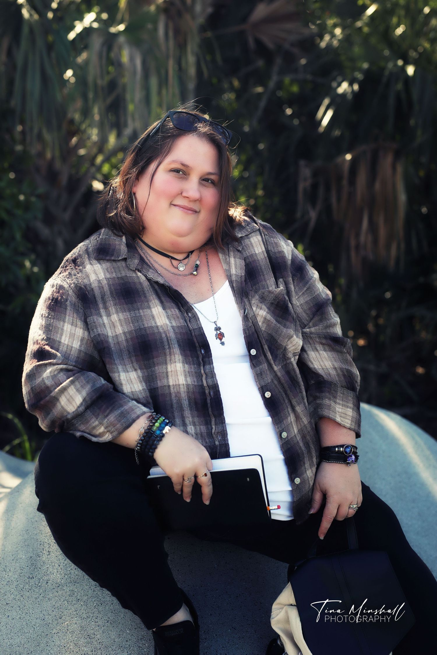 Woman in a plaid flannel shirt sitting confidently on a boulder, casual women's portrait session