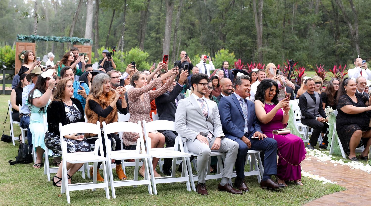 Wedding guests laughing and taking photos on their phones during the ceremony, Jacksonville, FL