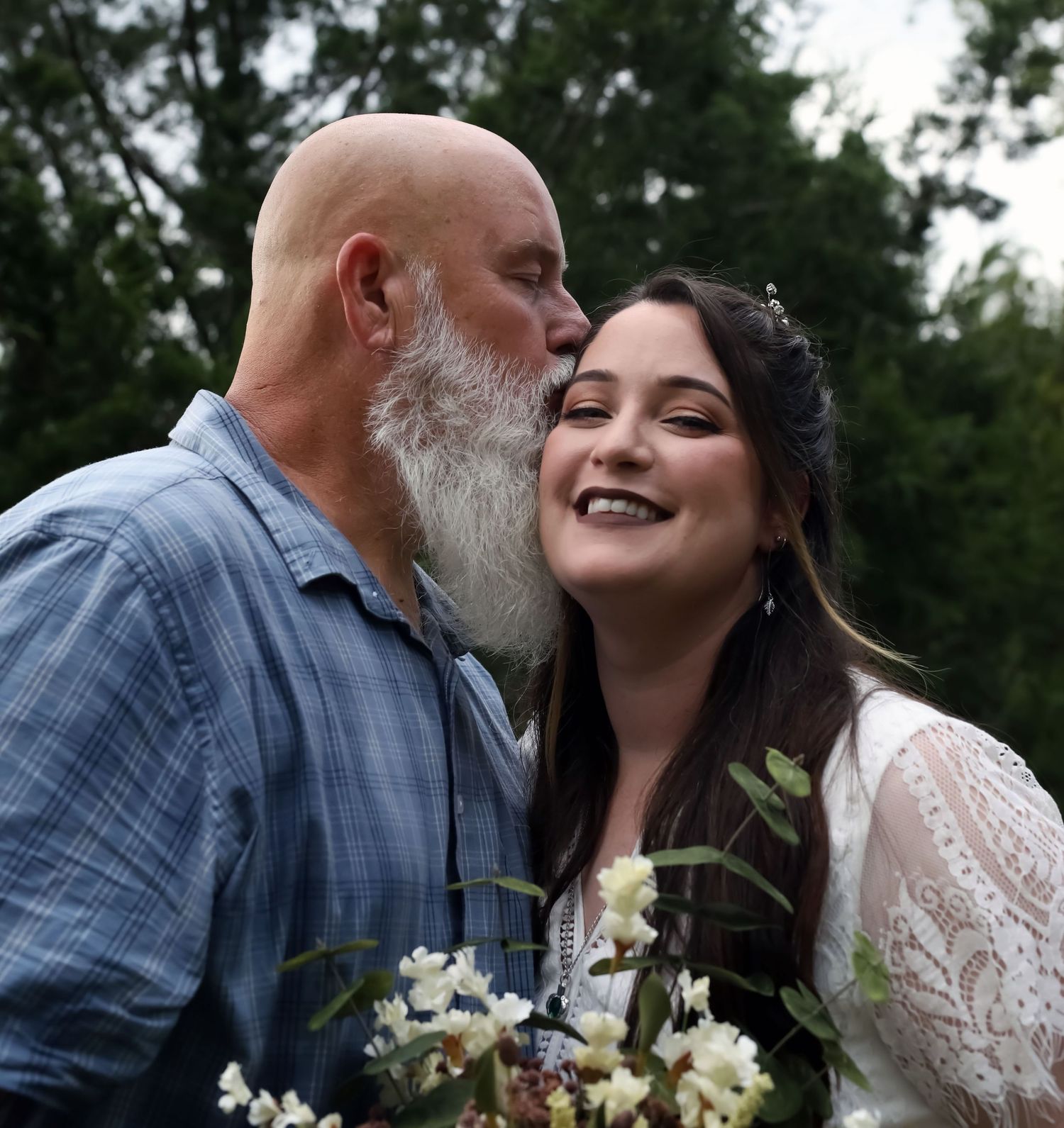 Father kissing his daughter's cheek as she laughs, candid father-daughter moment