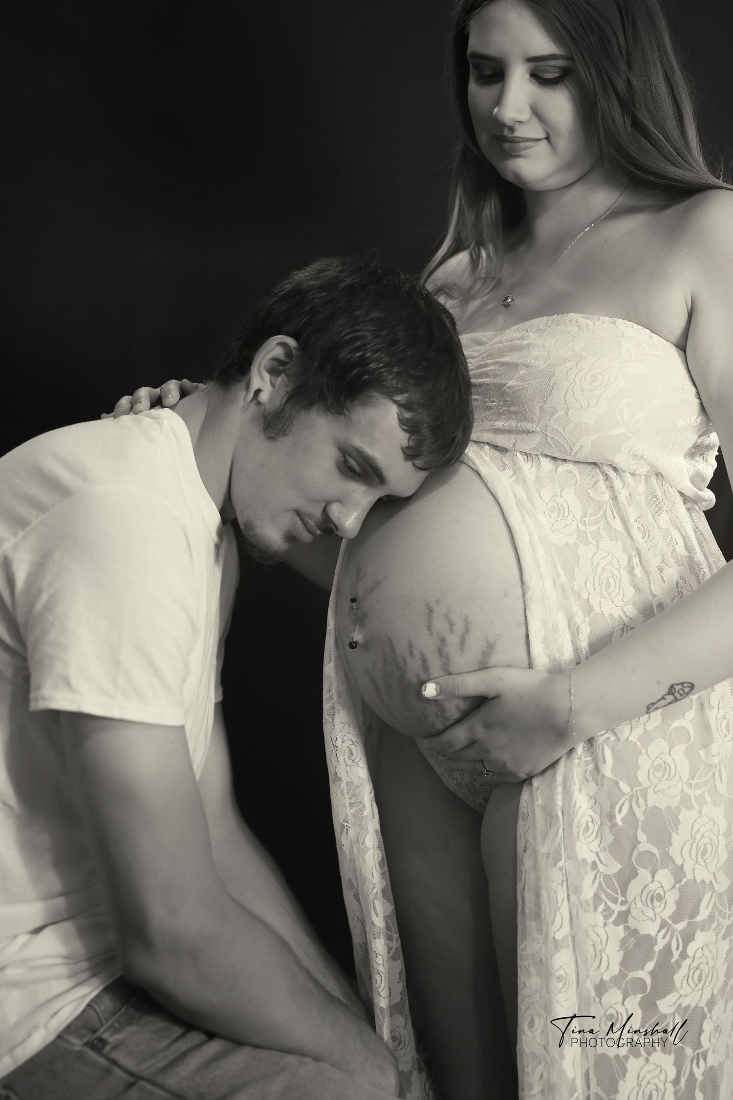 Black and white maternity portrait, partner gently touching pregnant belly