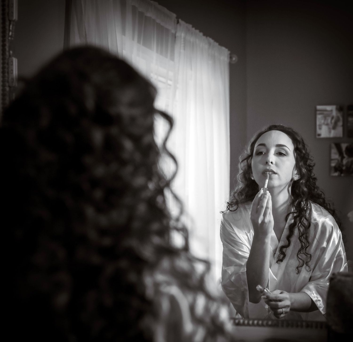 Woman applying lipstick in a mirror, candid getting-ready moment shot in black and white