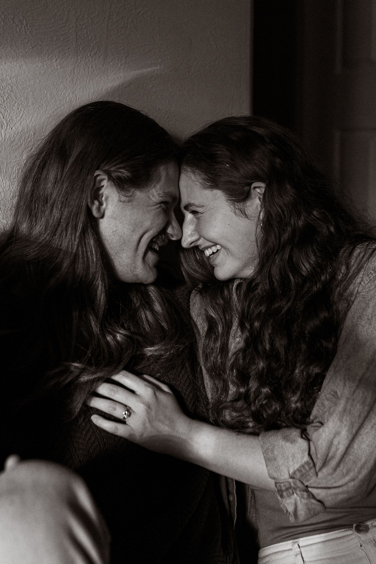 Black and white portrait of a smiling couple sharing an intimate, joyful moment with foreheads nearly touching.