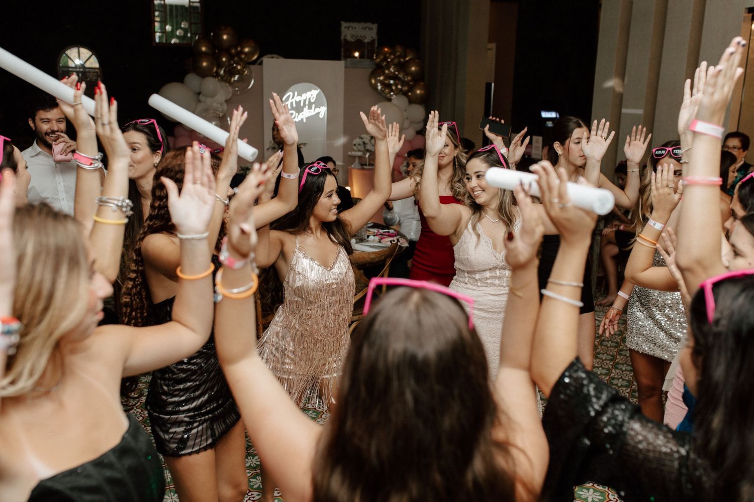 Energetic crowd of women dancing with hands raised at a festive party celebration.