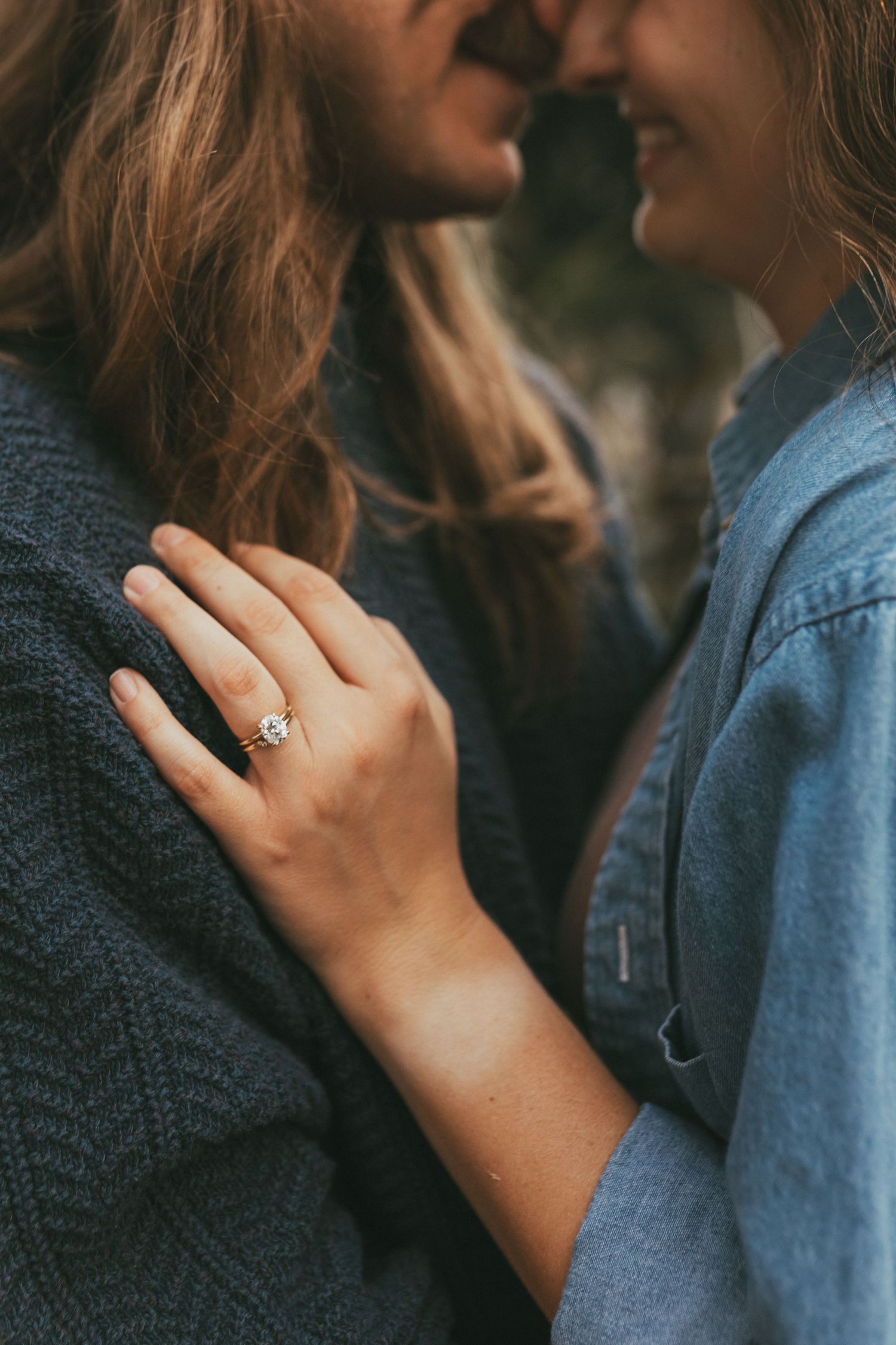 Close-up of couple nearly kissing with bride's hand showing a sparkling diamond engagement ring.