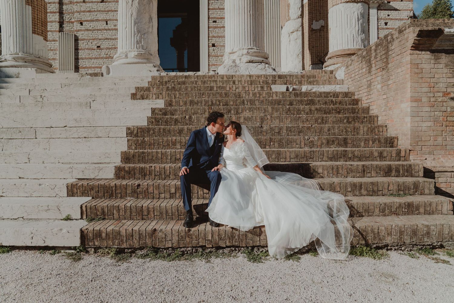 Newlywed couple sitting on the steps of the Capitolium in Brescia, Italy.