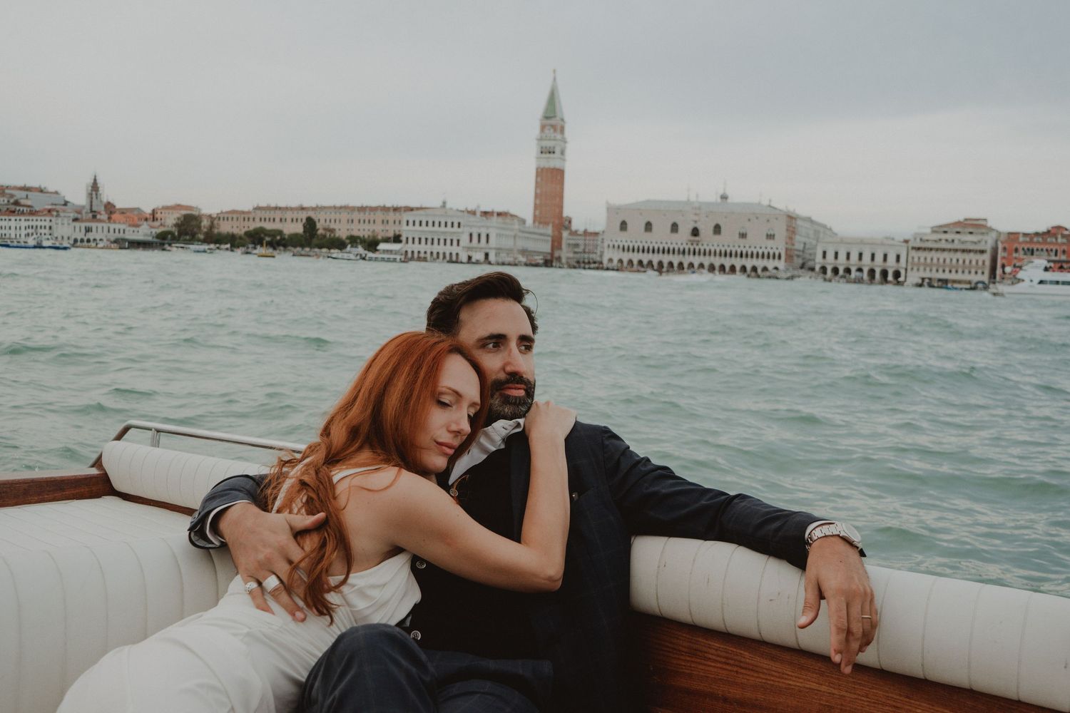 Newlywed couple on a boat with St. Mark's Square in the background in Venice, Italy.