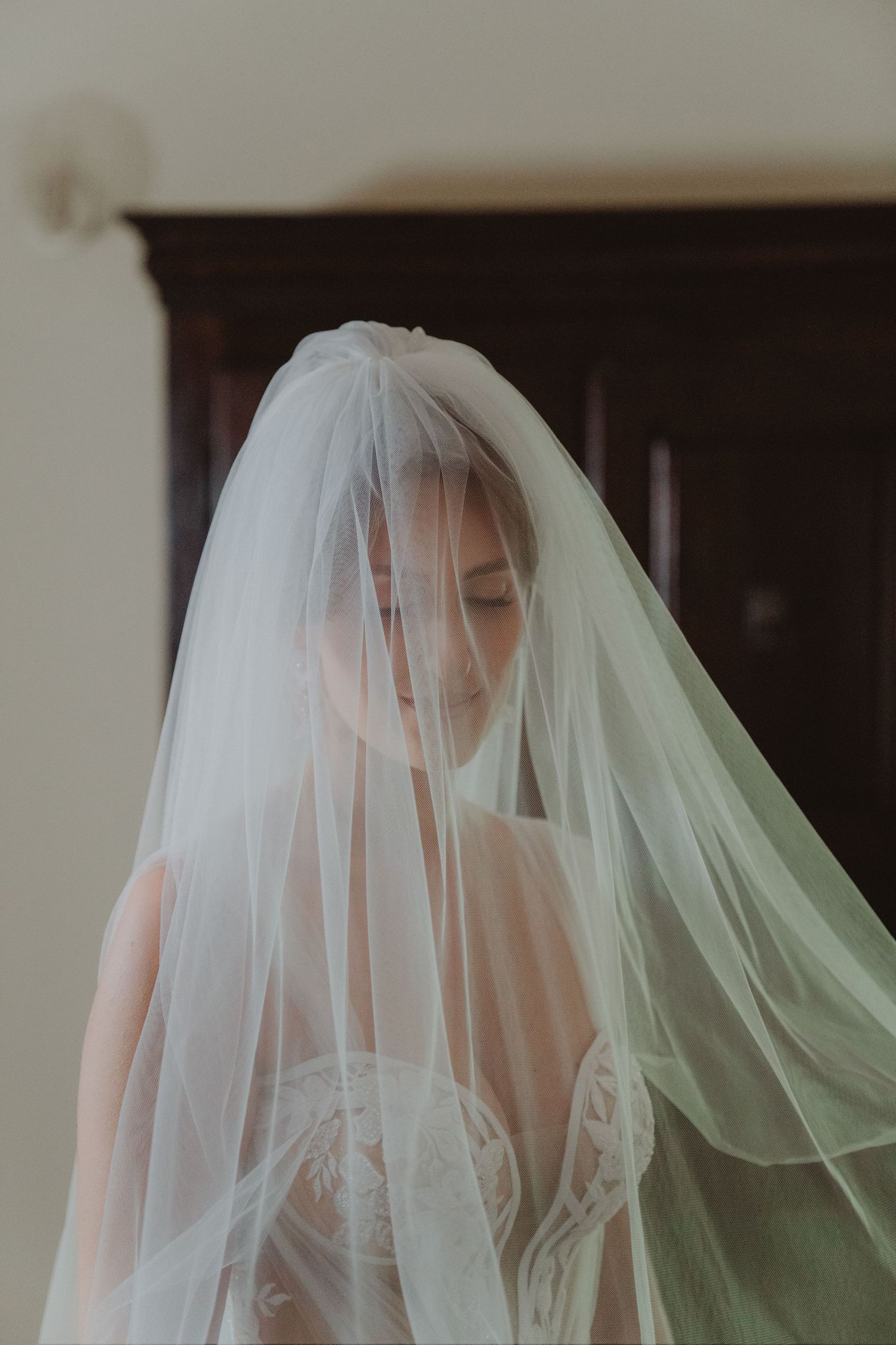 Bride smiling beneath her veil, with her eyes visible and looking toward the camera.