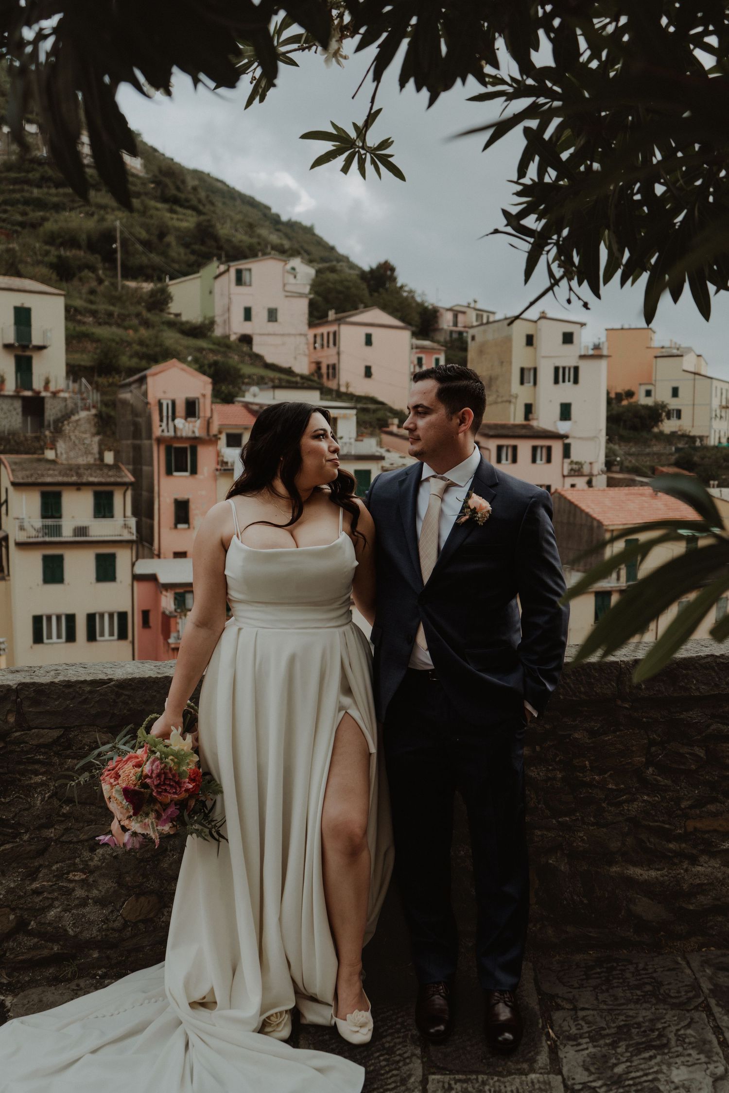 Newlywed couple with the picturesque village of Riomaggiore in the background.