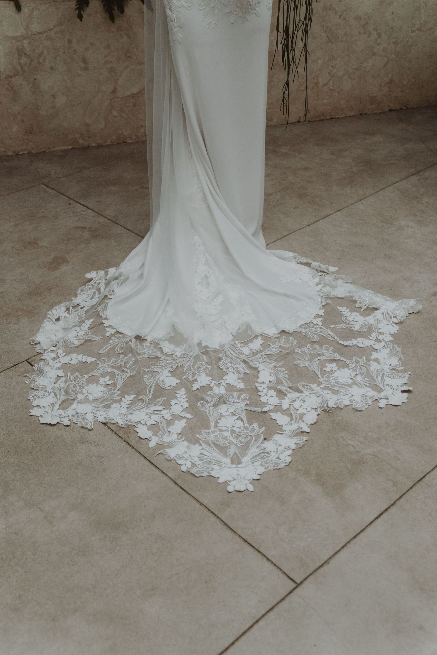 Close-up detail of a bride's wedding dress featuring delicate lace embroidery.