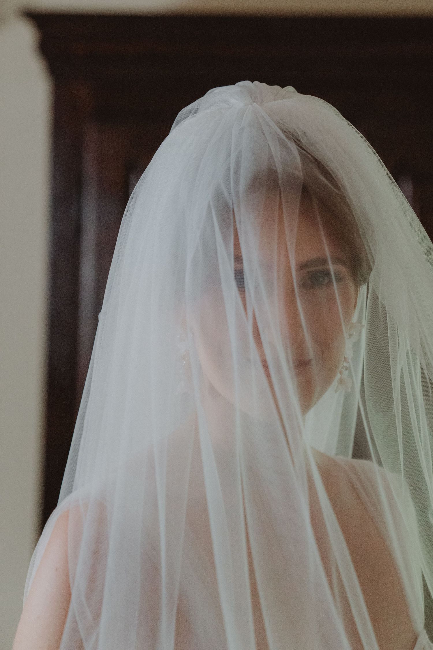 Bride smiling beneath her veil, with her eyes visible and looking toward the camera.