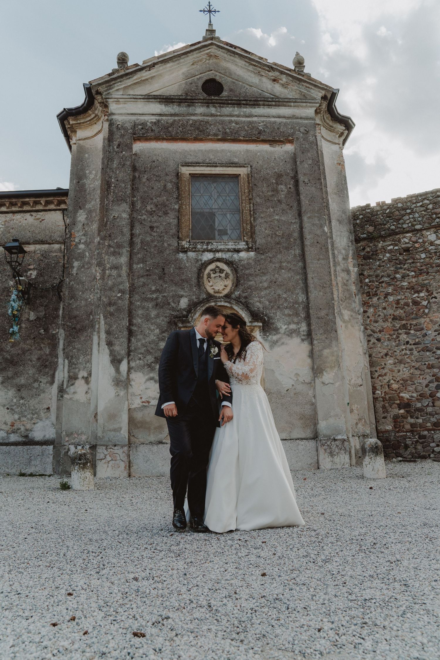Bride and groom standing face to face with a beautiful historic church in the background.