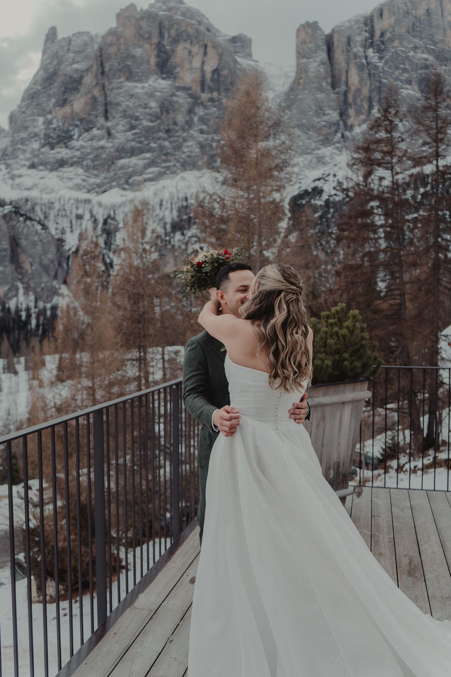 Newlywed couple kissing on a terrace overlooking the Dolomites, Italy.