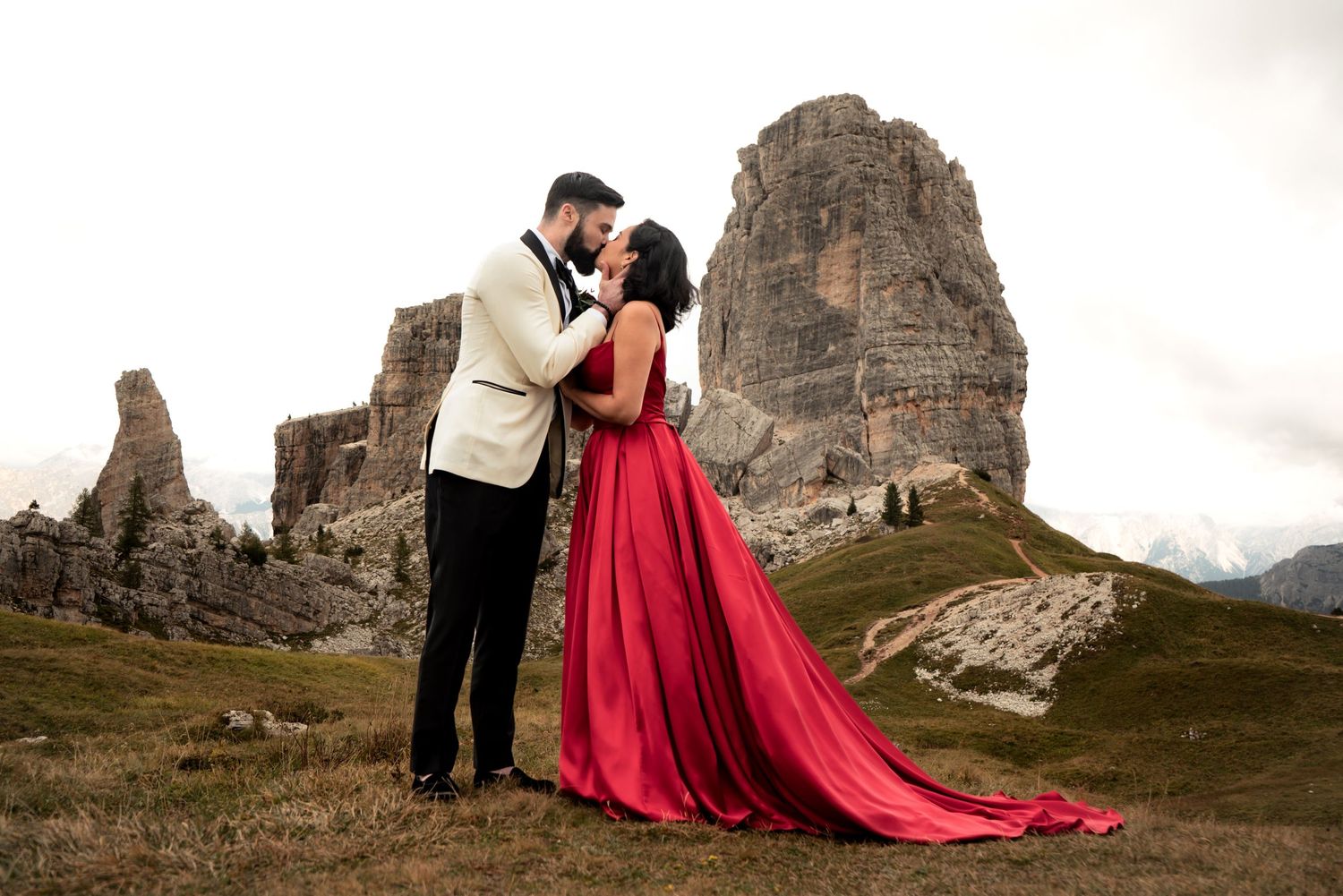 Romantic kiss between a newlywed couple with the Dolomites in the background.