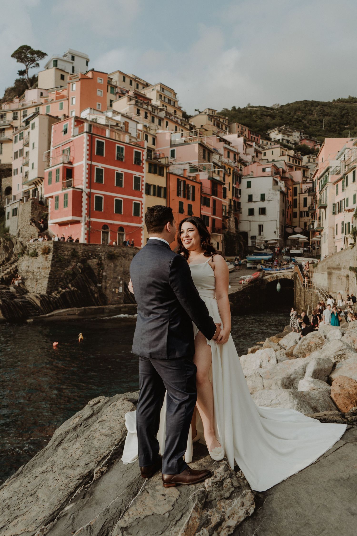 Newlywed couple with the picturesque village of Riomaggiore in the background.