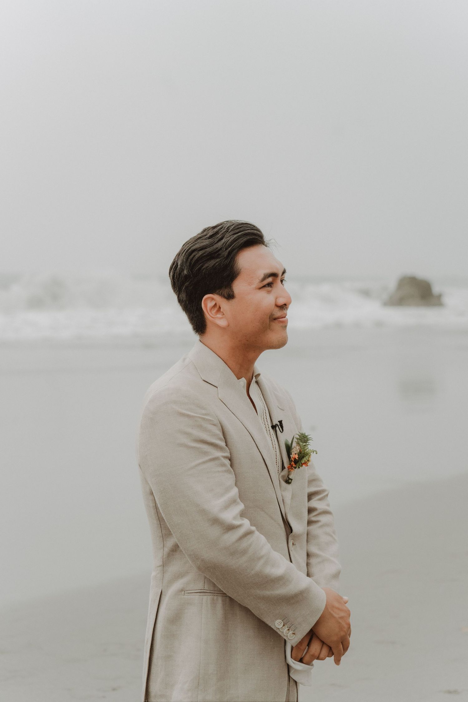 Groom standing on the beach with the sea in the background on his wedding day.