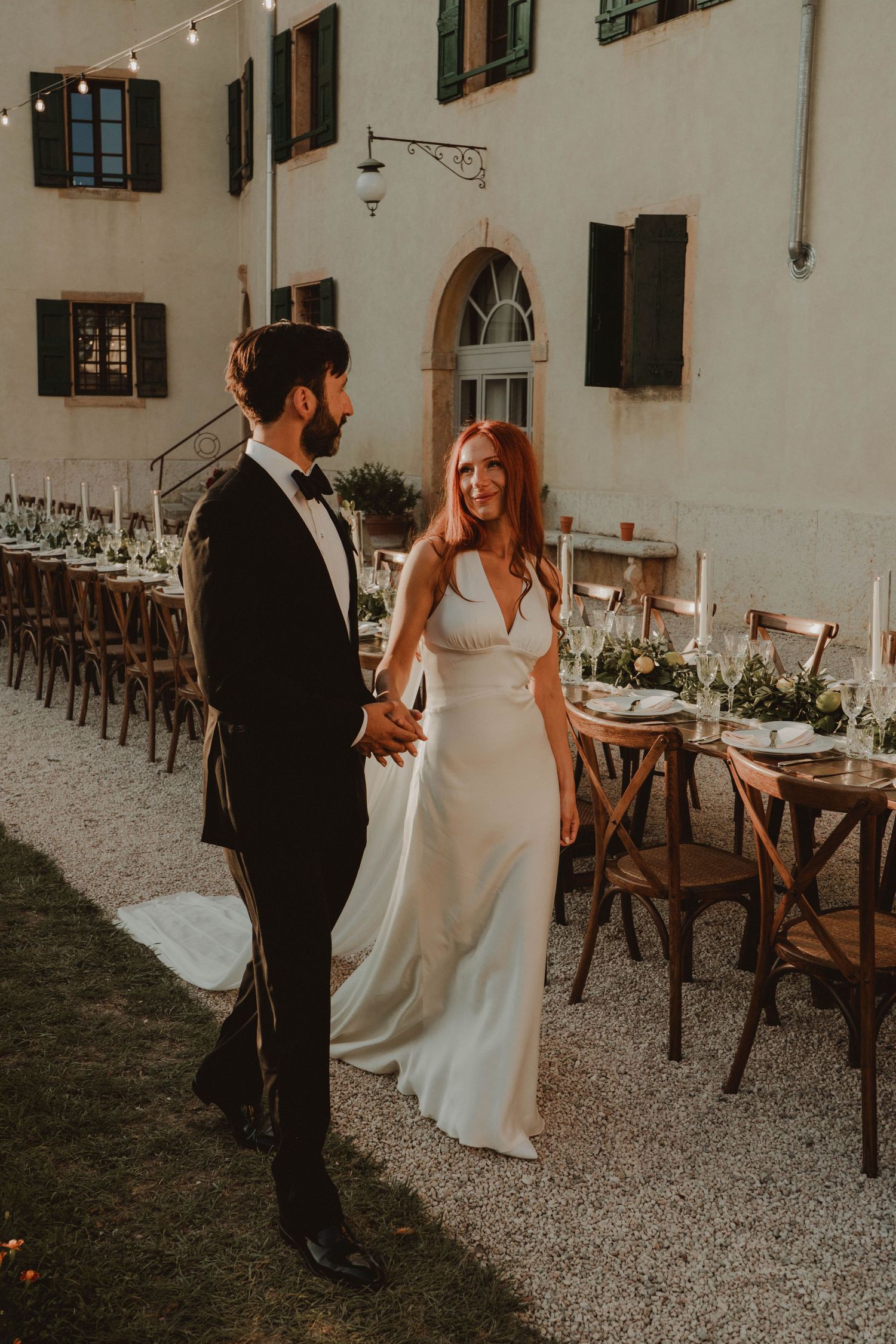 Newlywed couple with beautifully decorated wedding tables in the background.