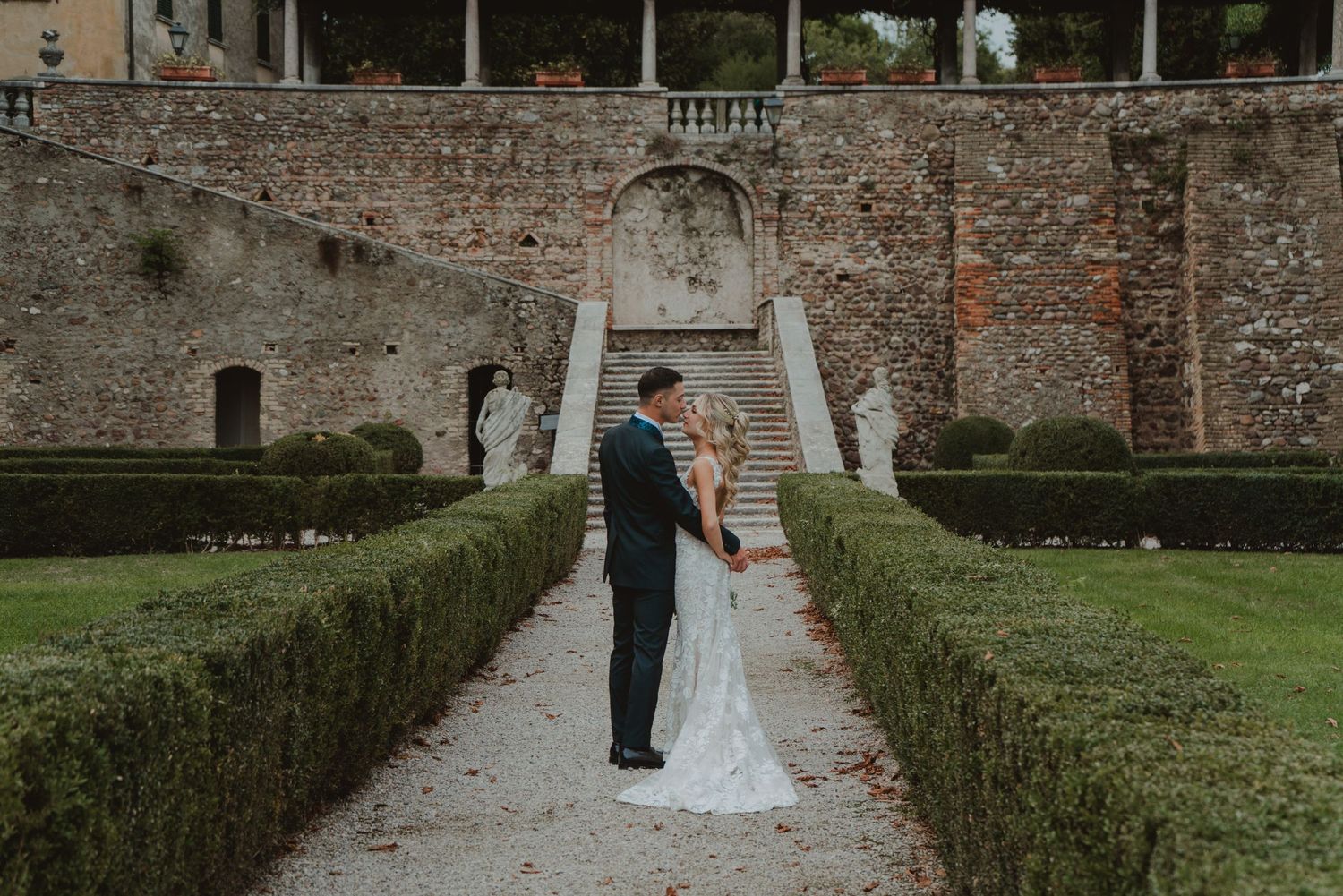 Bride and groom sharing an intimate moment just before their kiss in a historic villa and village setting.