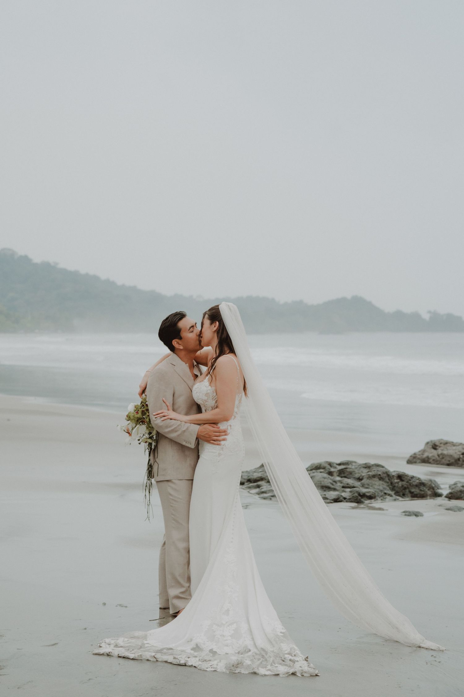 Newlywed couple facing each other and kissing on a beach in Costa Rica.
