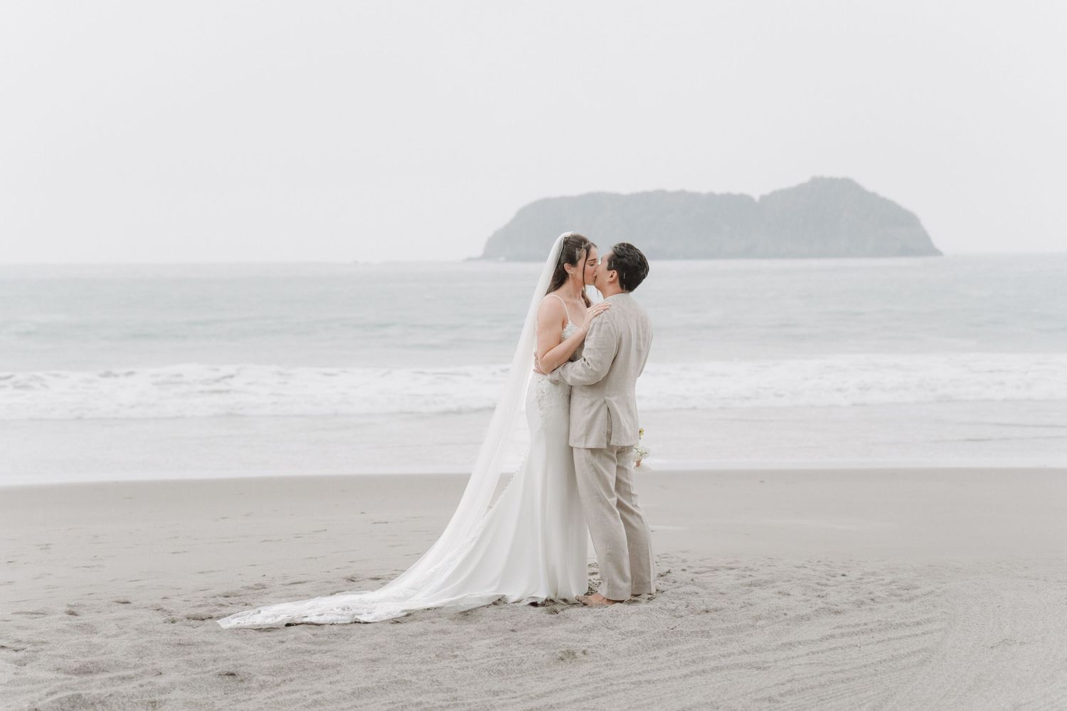 Newlywed couple running together along the beach on their wedding day.
