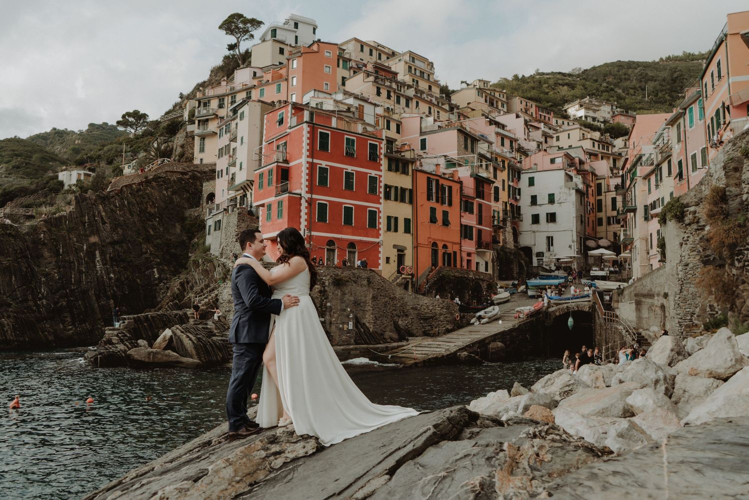 Newlywed couple with the picturesque village of Riomaggiore in the background.