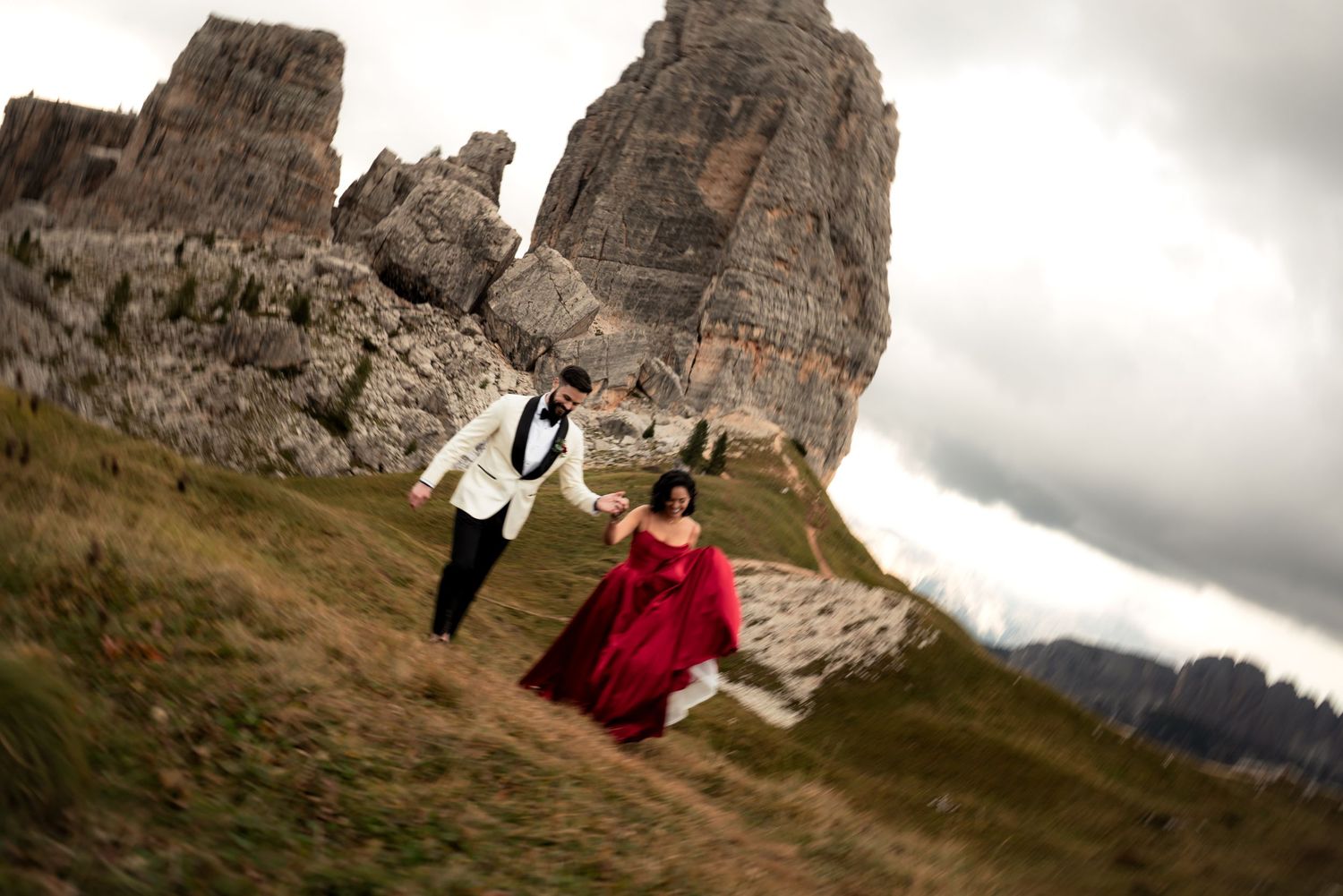 Motion-blurred newlywed couple standing on a mountaintop in the Dolomites.