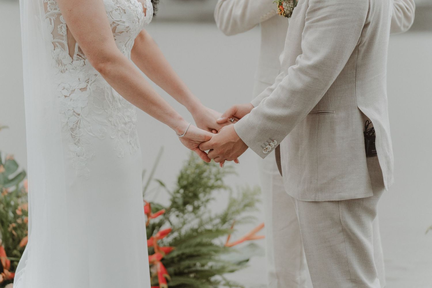 Bride and groom holding hands during the exchange of wedding rings.