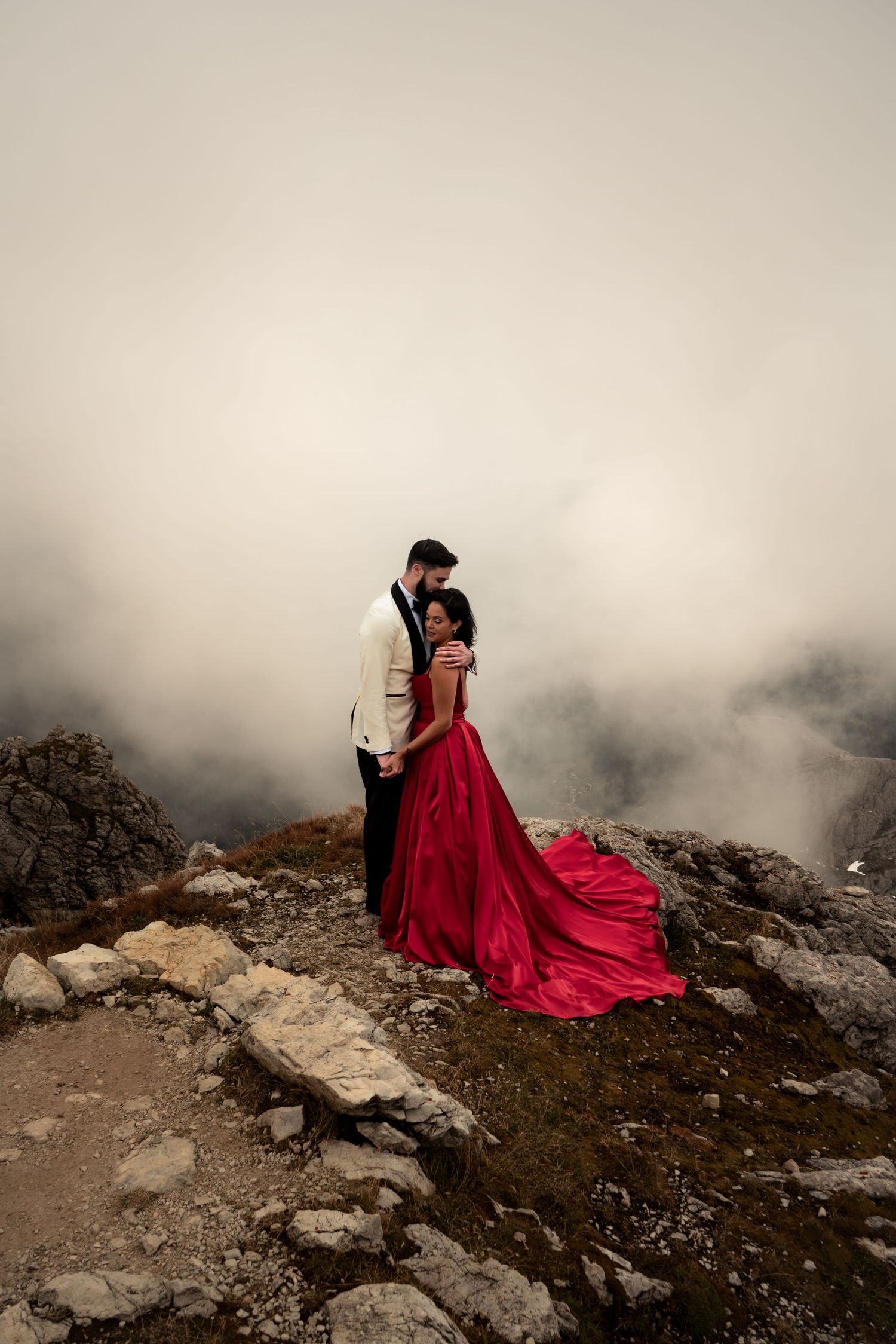 Newlywed couple embracing on a mountaintop in the Dolomites, surrounded by a magical atmosphere.