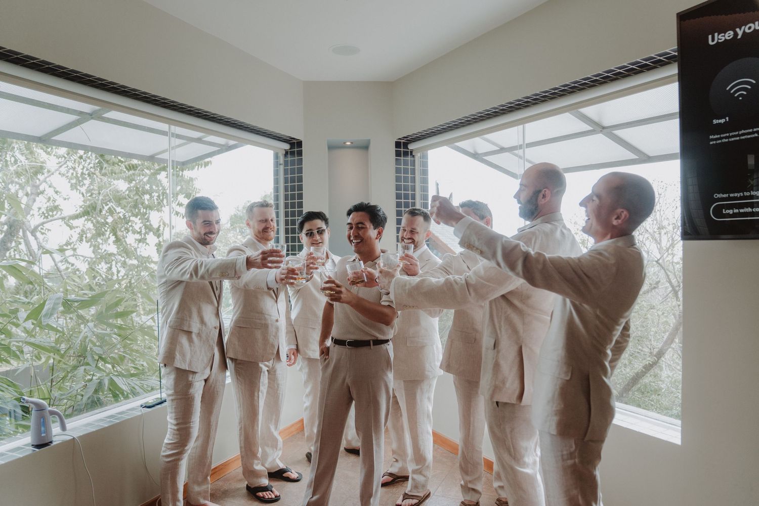 Groom celebrating and raising a toast with his groomsmen on his wedding day.