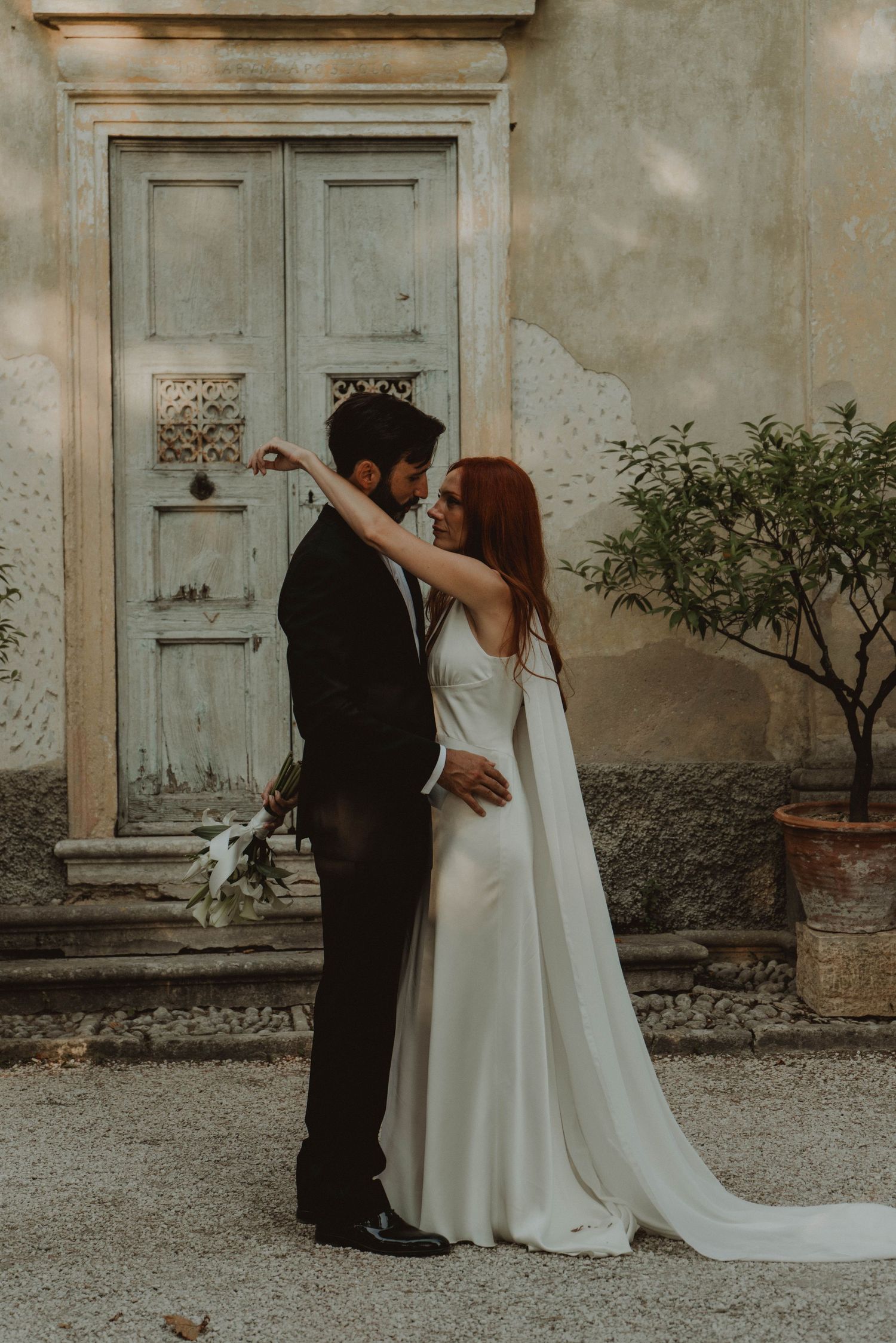 Newlywed couple standing in front of a historic chapel.