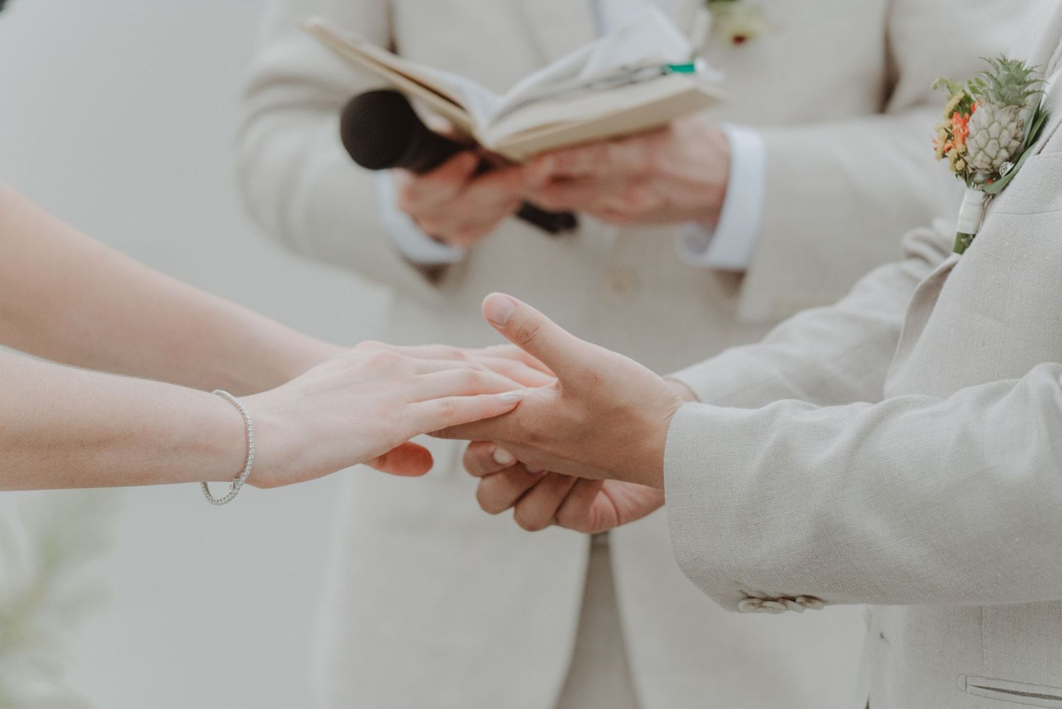 Bride and groom holding hands during the exchange of wedding rings.