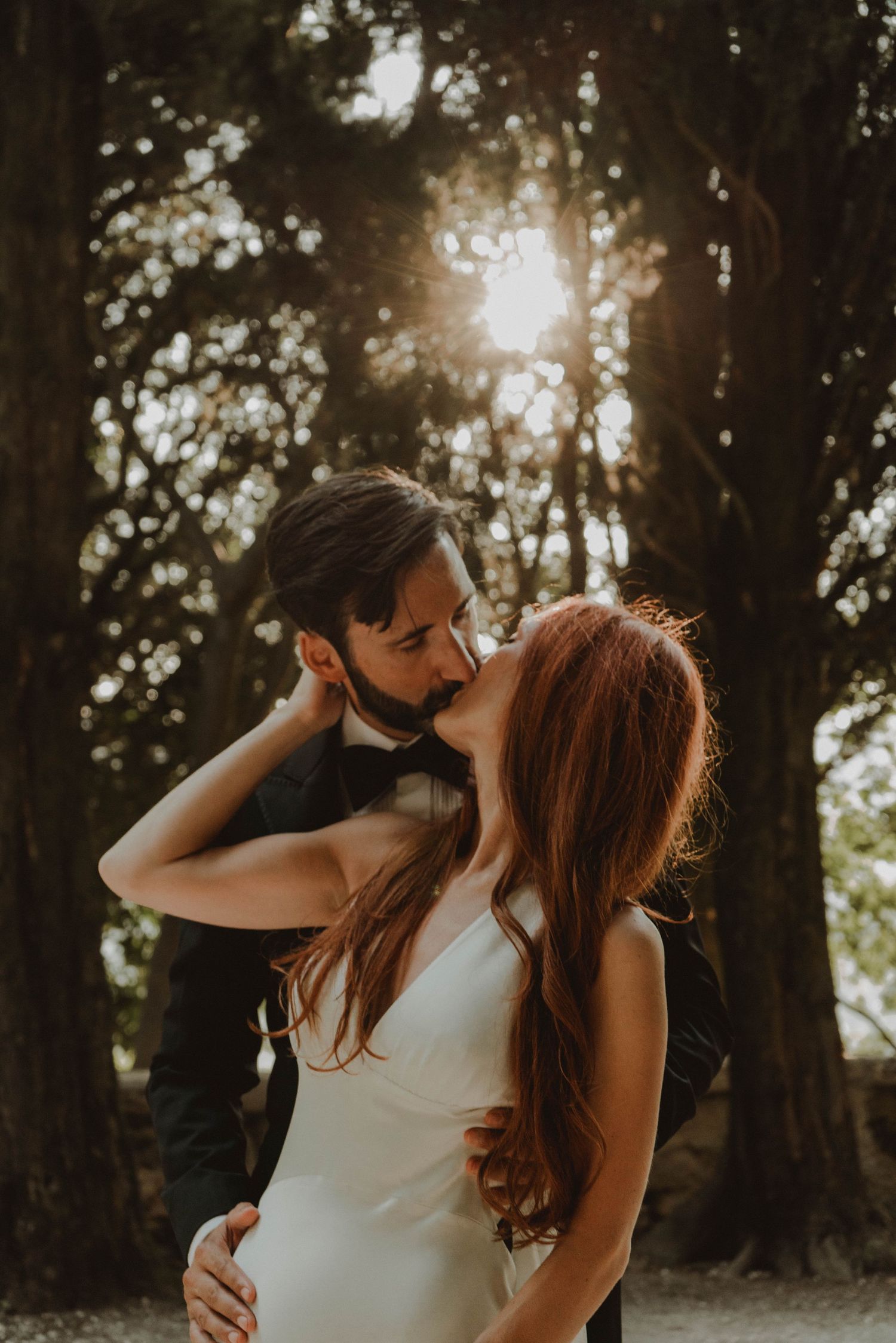 Newlywed couple kissing at a historic villa in Verona, Italy, with a beautiful sunset in the background.