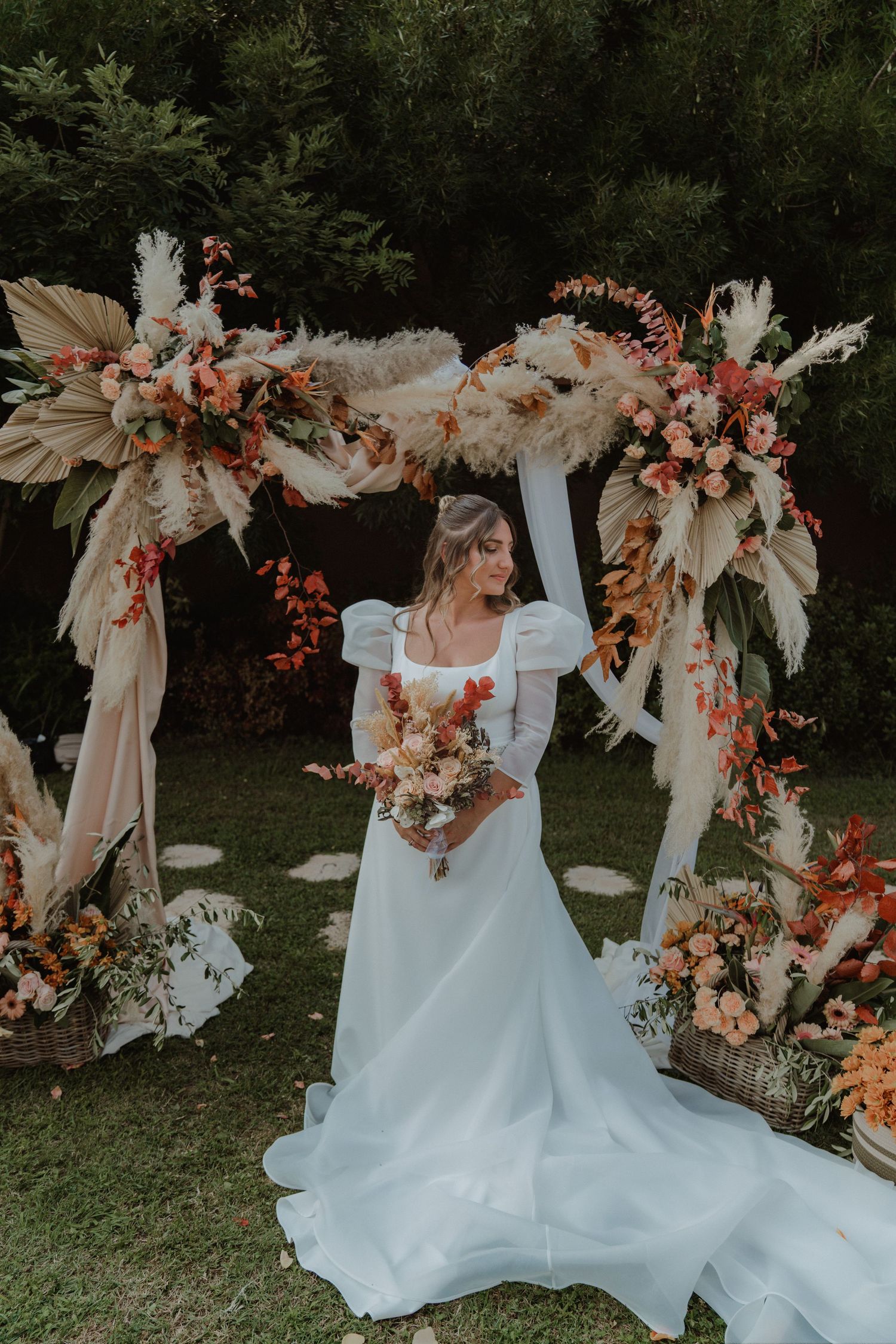 Portrait of a bride framed by a beautiful floral wedding arch.