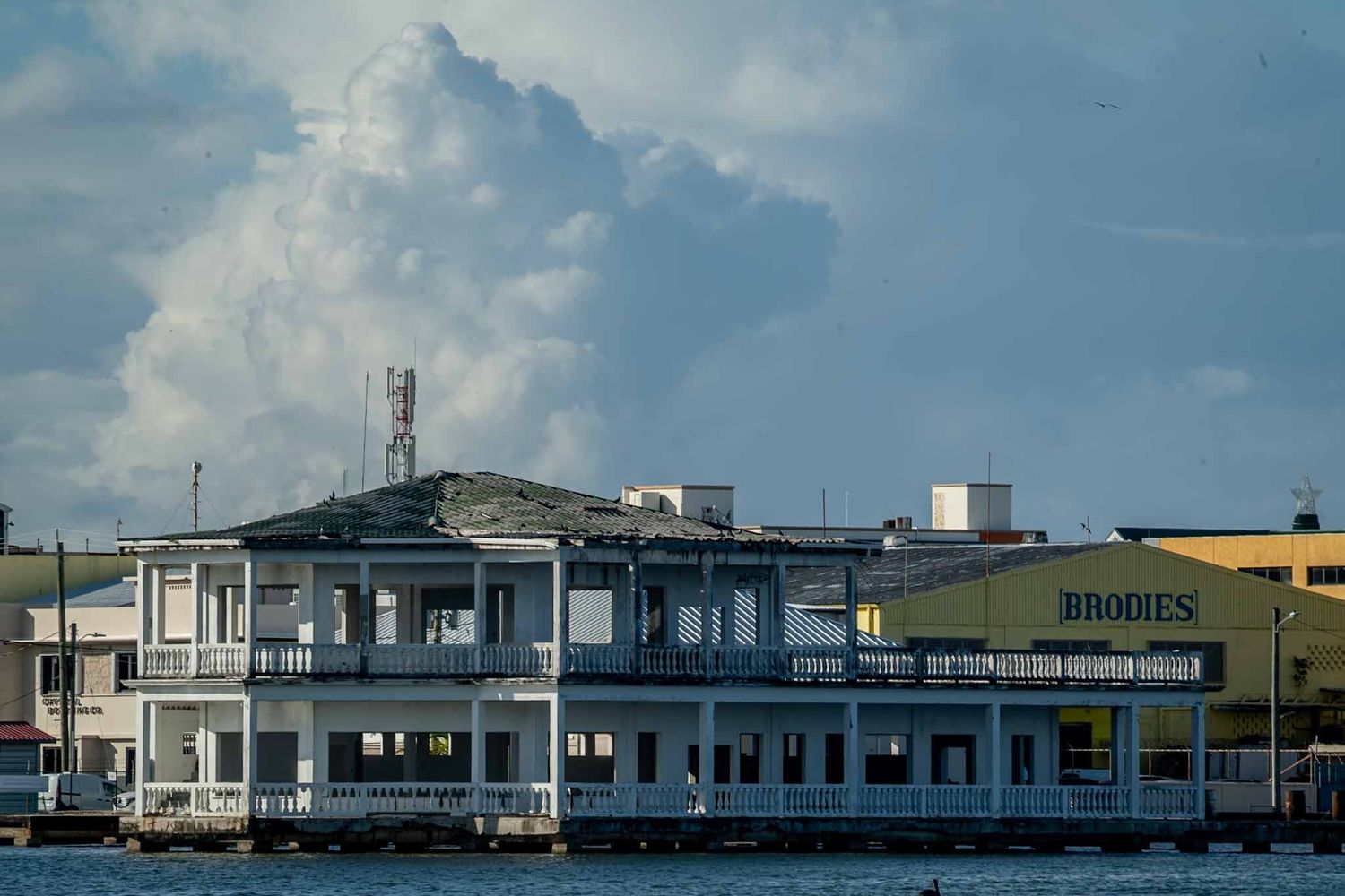 Waterfront restaurant with white exterior and blue trim sits along a dock under cloudy skies.