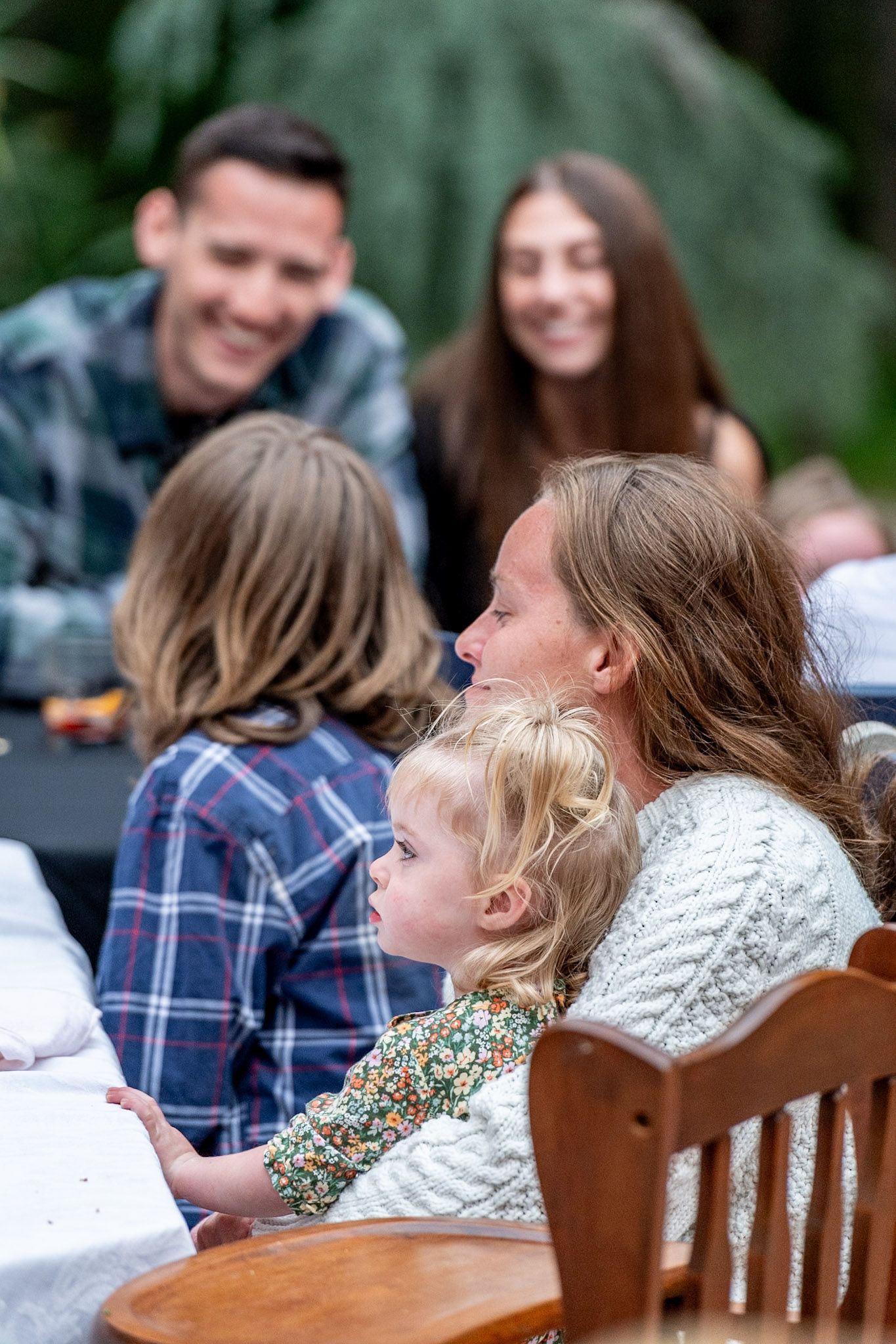 Outdoor gathering with wooden chairs and people enjoying a social event.
