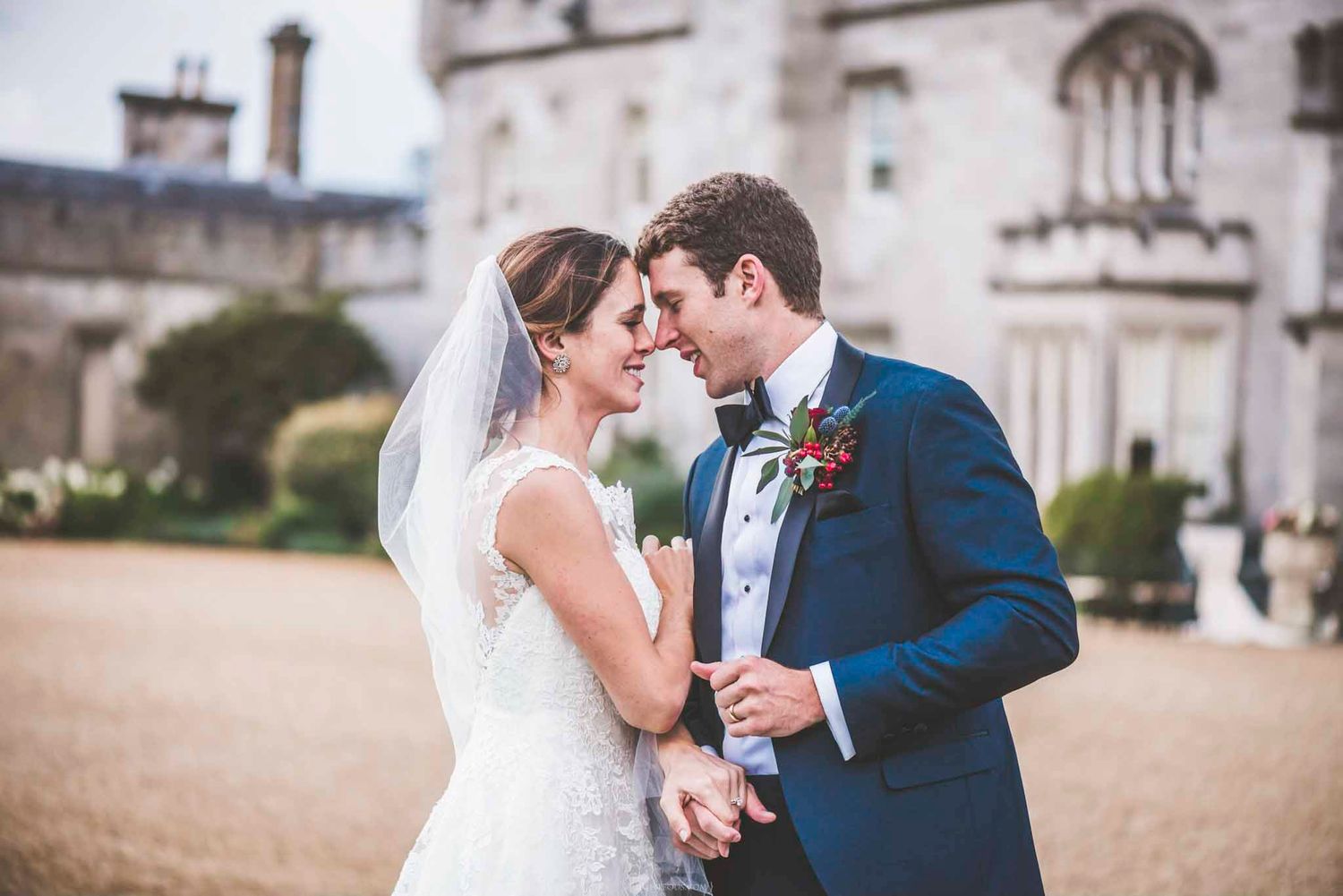 Bride and groom sharing an intimate moment in front of a grand castle on their wedding day.