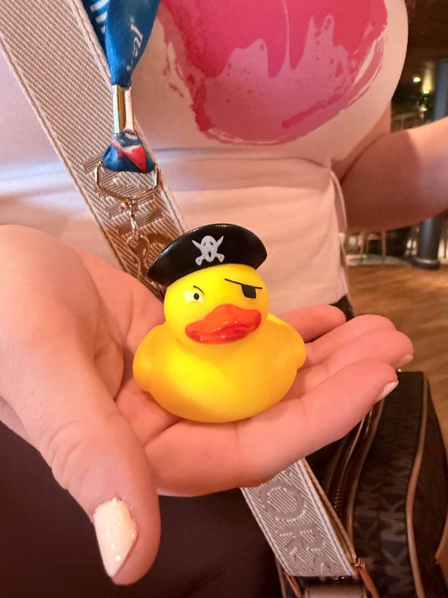 A sequence of photos showing a small yellow rubber duck toy with a pirate eye patch being held against a pink background.