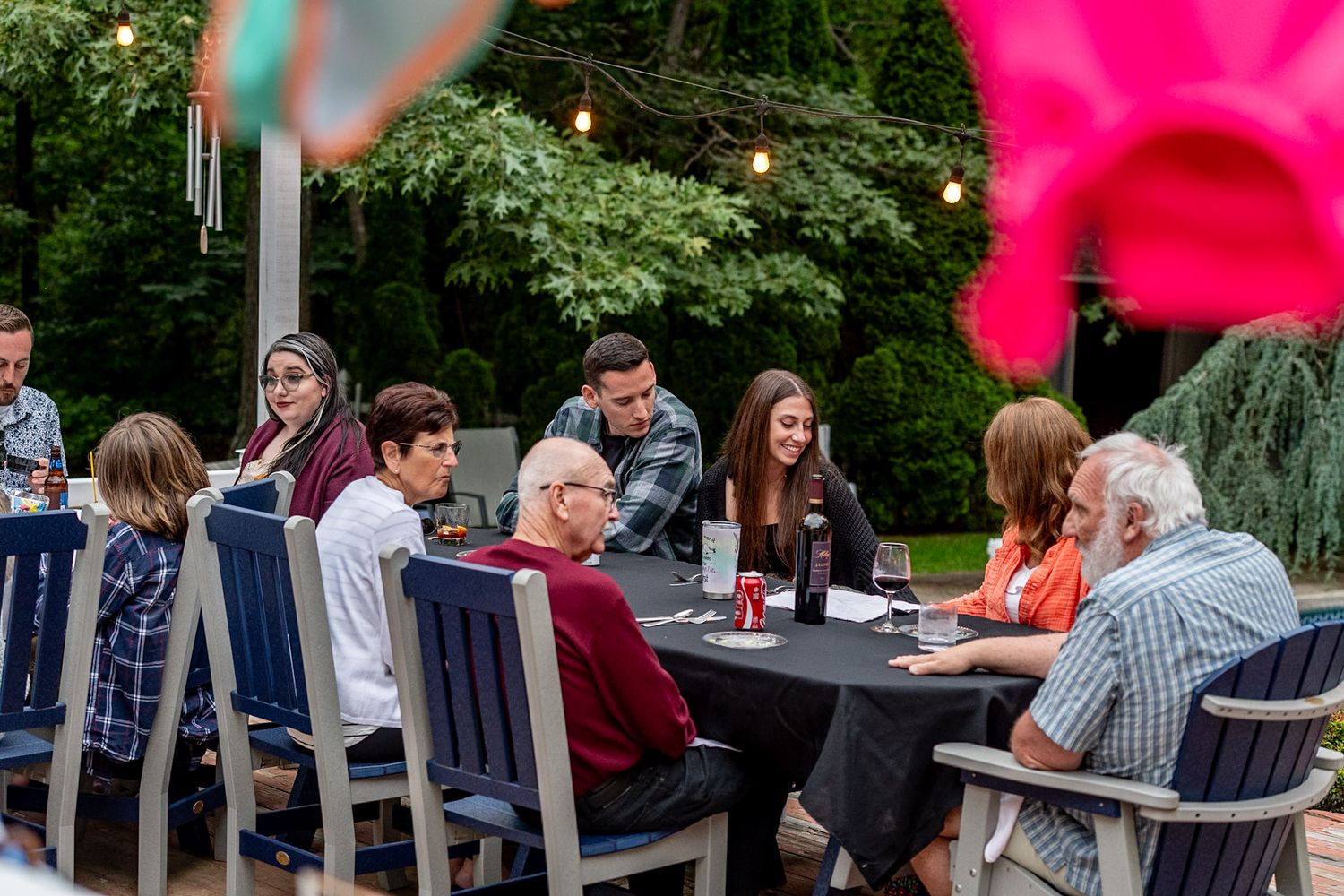 Garden party setting with tables and chairs arranged outdoors among greenery.