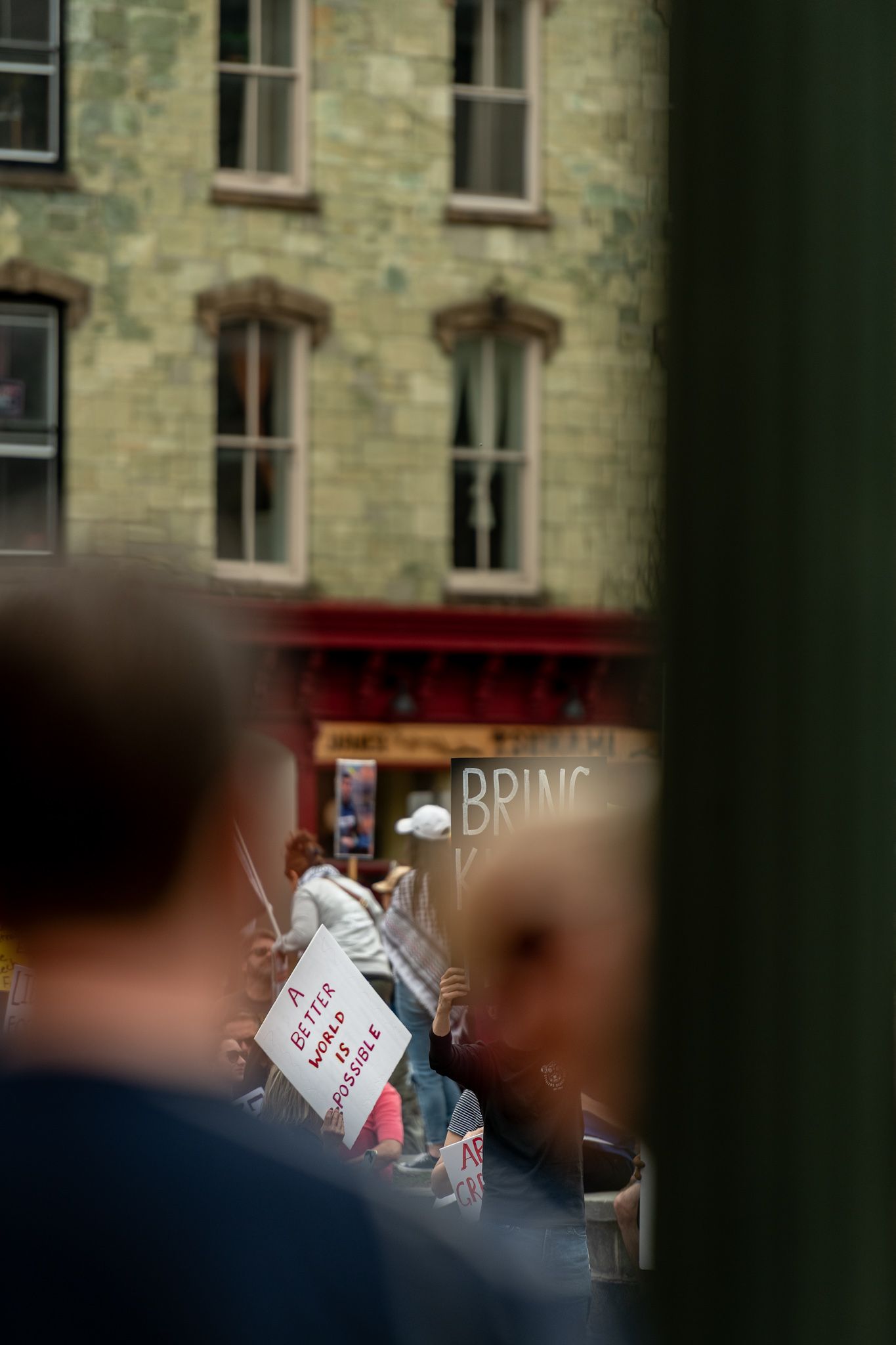 Protest signs visible through window frames of stone building.