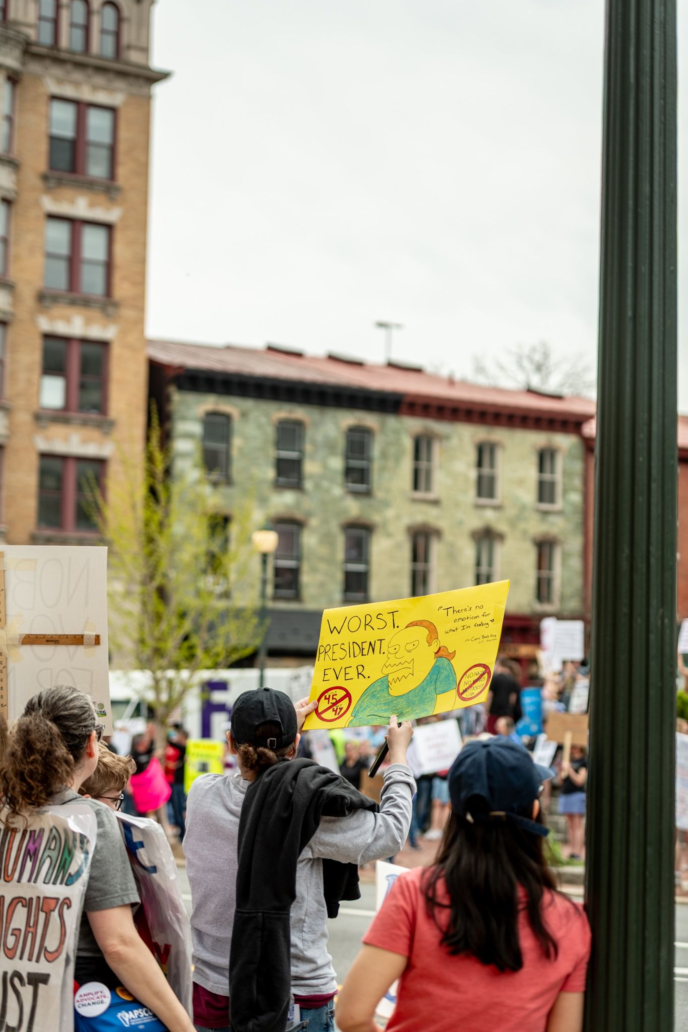Protesters holding signs aloft outside urban buildings during demonstration.