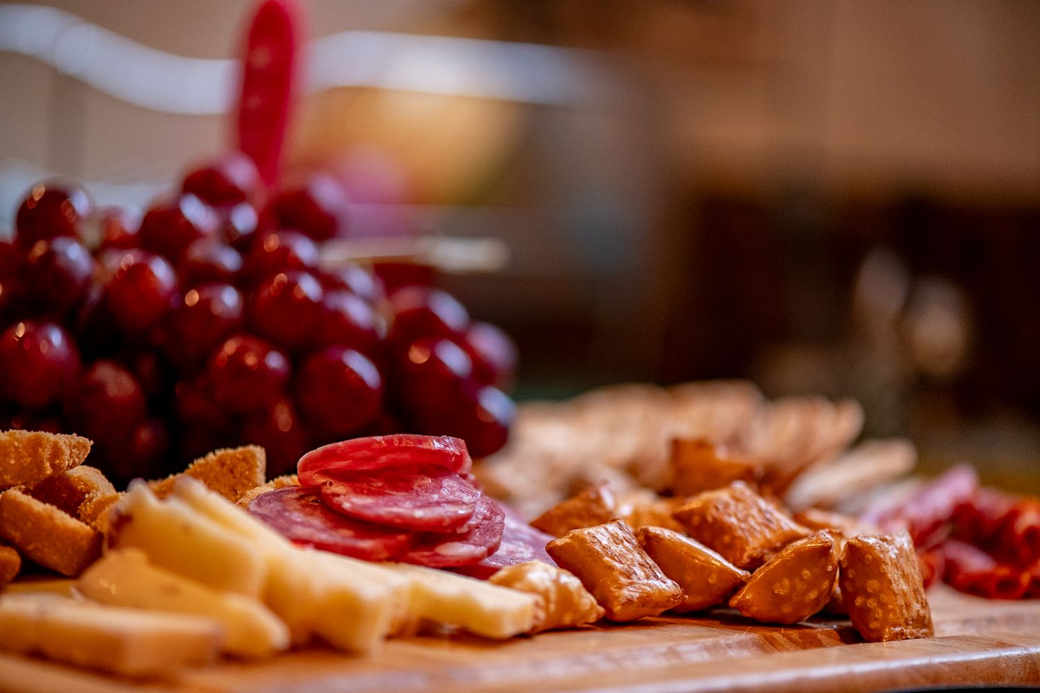 Close-up of charcuterie board with red grapes, crackers and cured meats.
