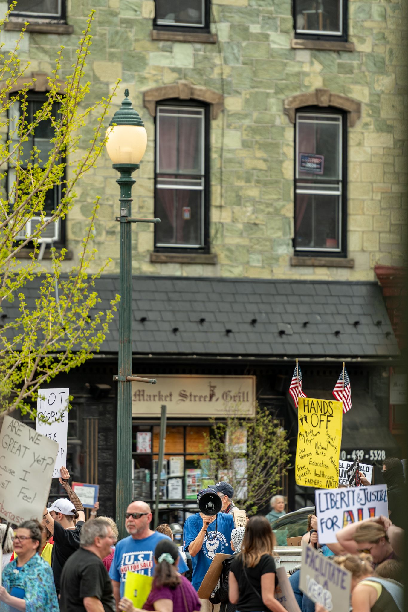 Stone building facade with protestors gathered outside holding signs and flags.