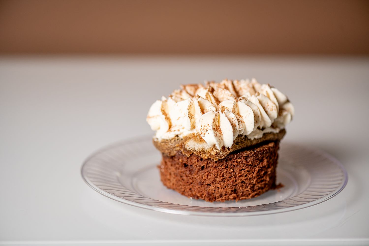 Chocolate dessert with whipped cream topping served on a white plate.