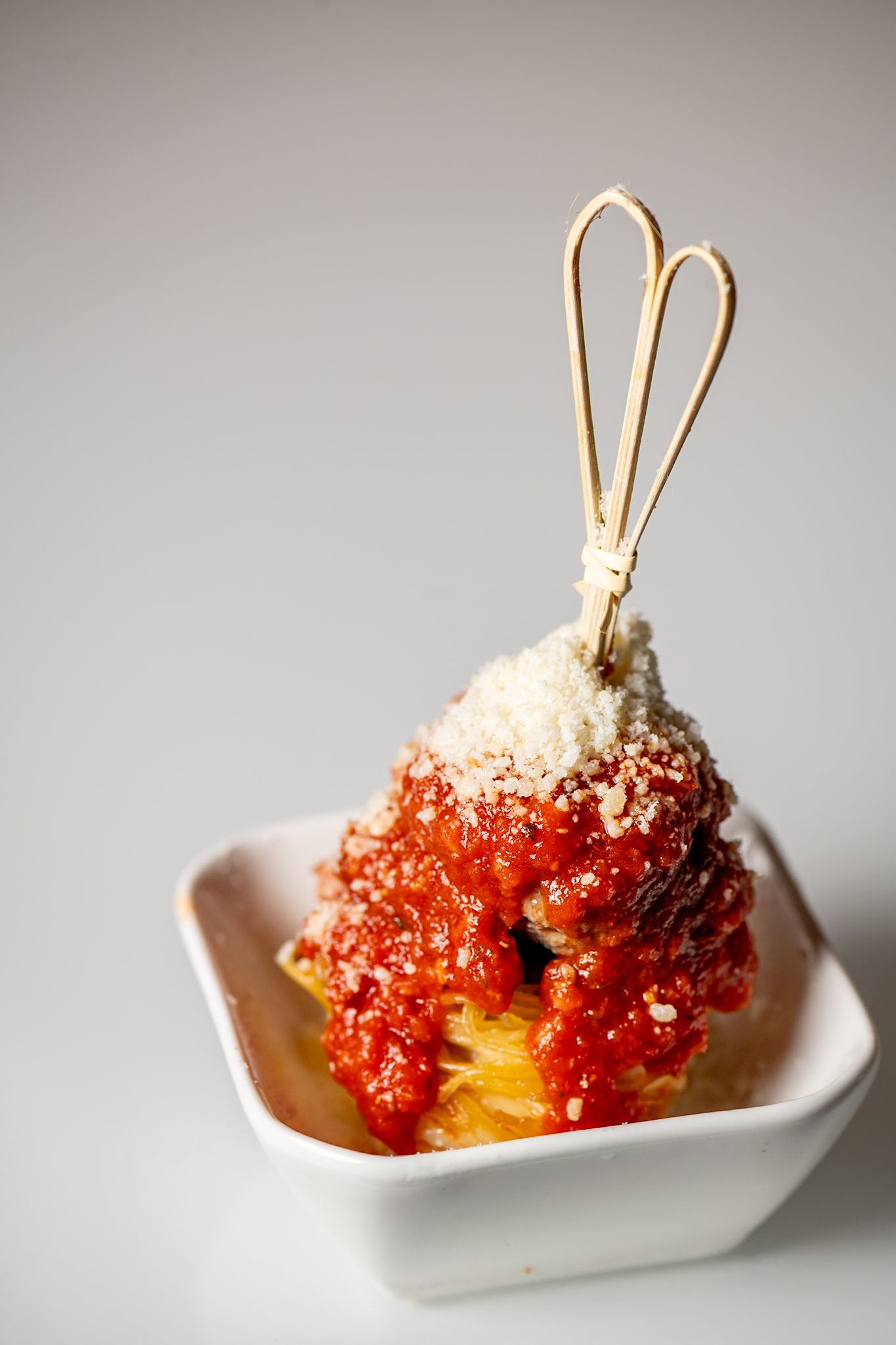 Asian-inspired appetizer with red sauce and chopsticks in a white serving dish.