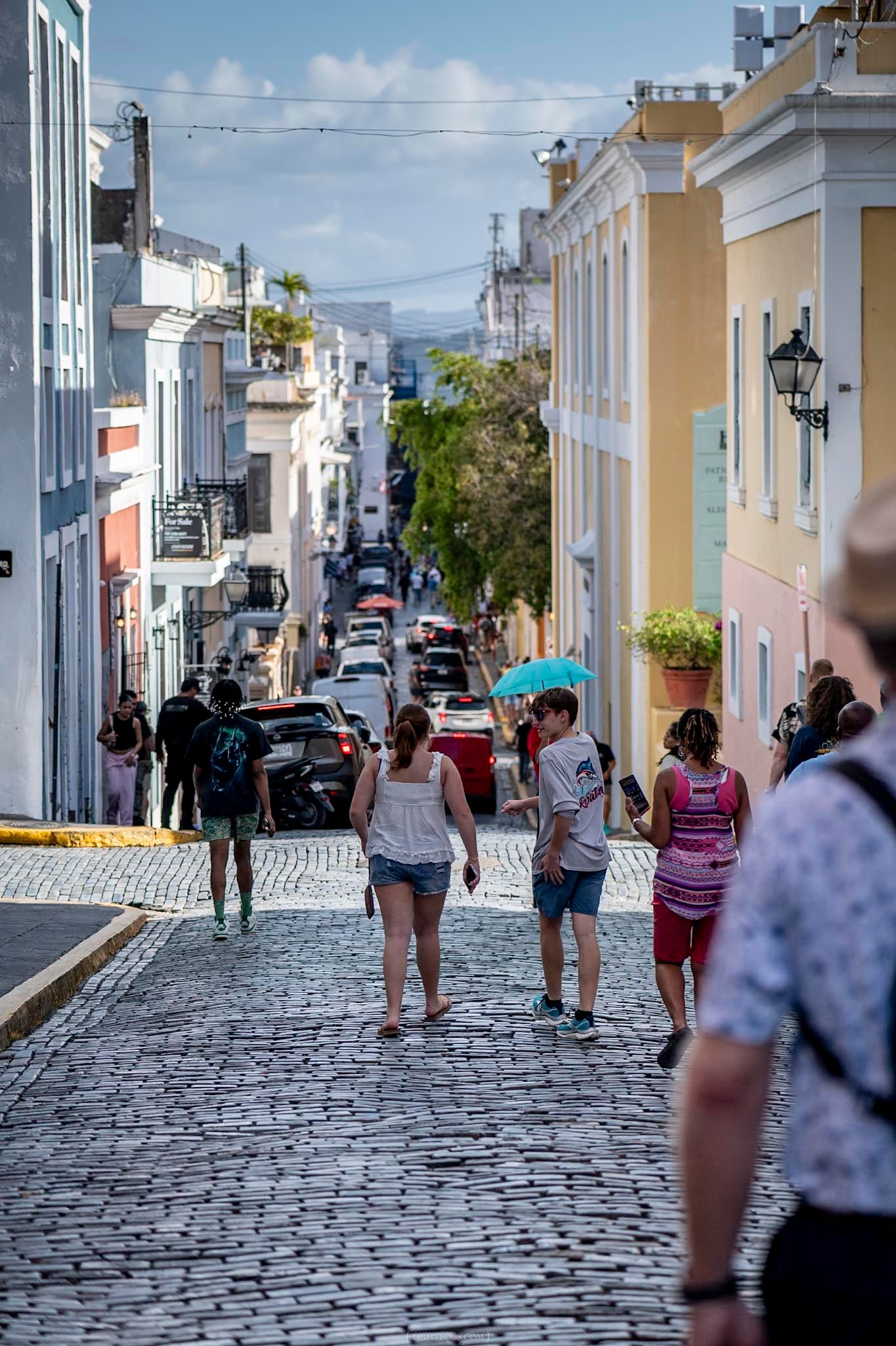 Tourists walking on historic cobblestone streets lined with colorful colonial buildings in Old San Juan, Puerto Rico.