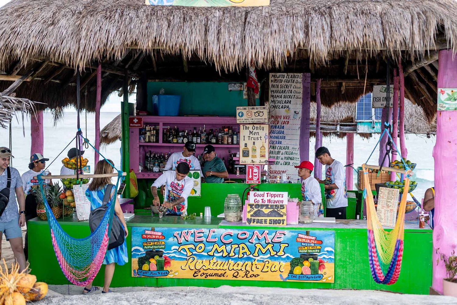 Colorful tiki-style beach bar with thatched roof and vibrant painted decorations.