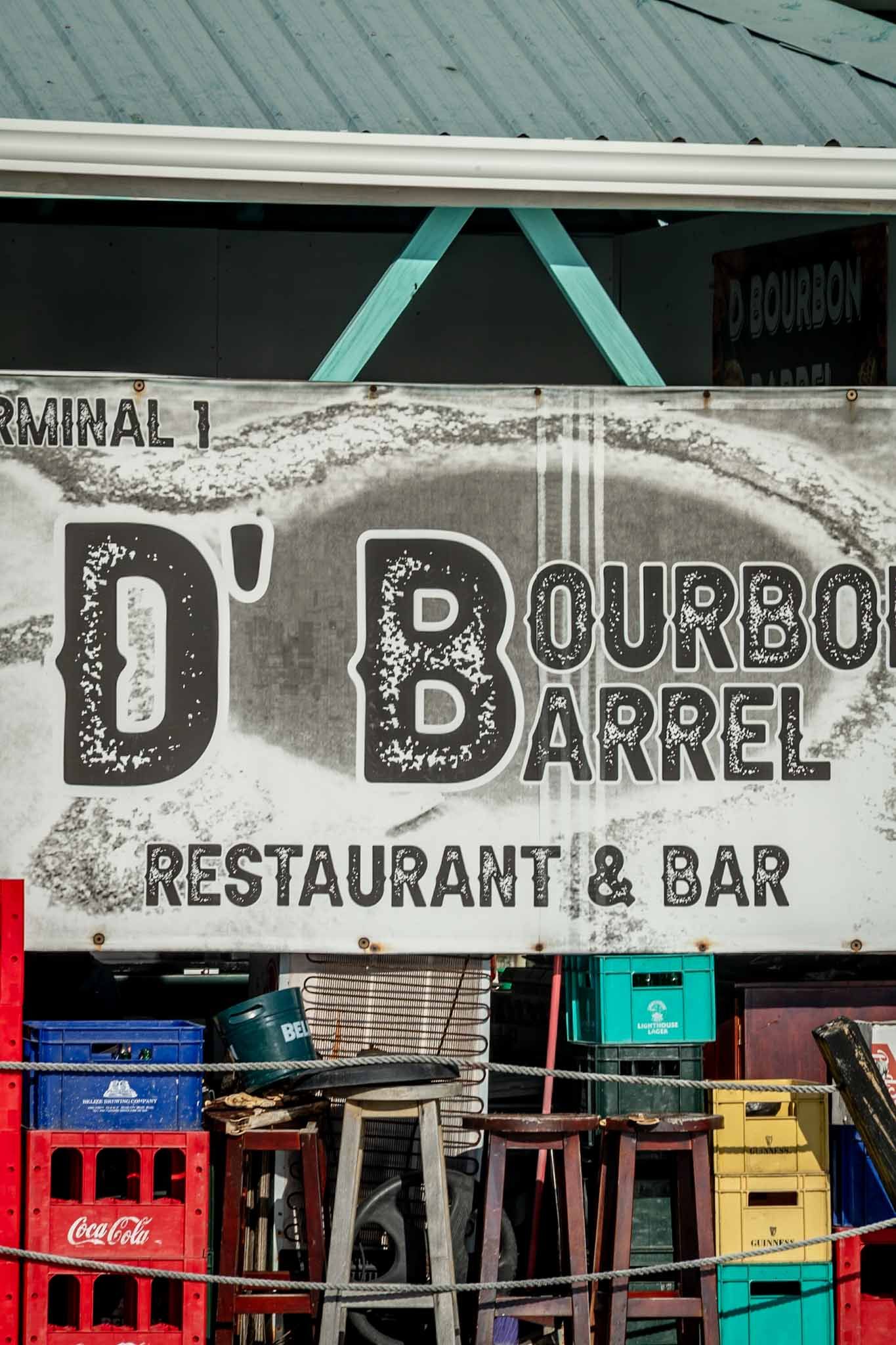 Weathered sign for D'Bourbon Restaurant & Bar with turquoise accents and Coca-Cola branding.