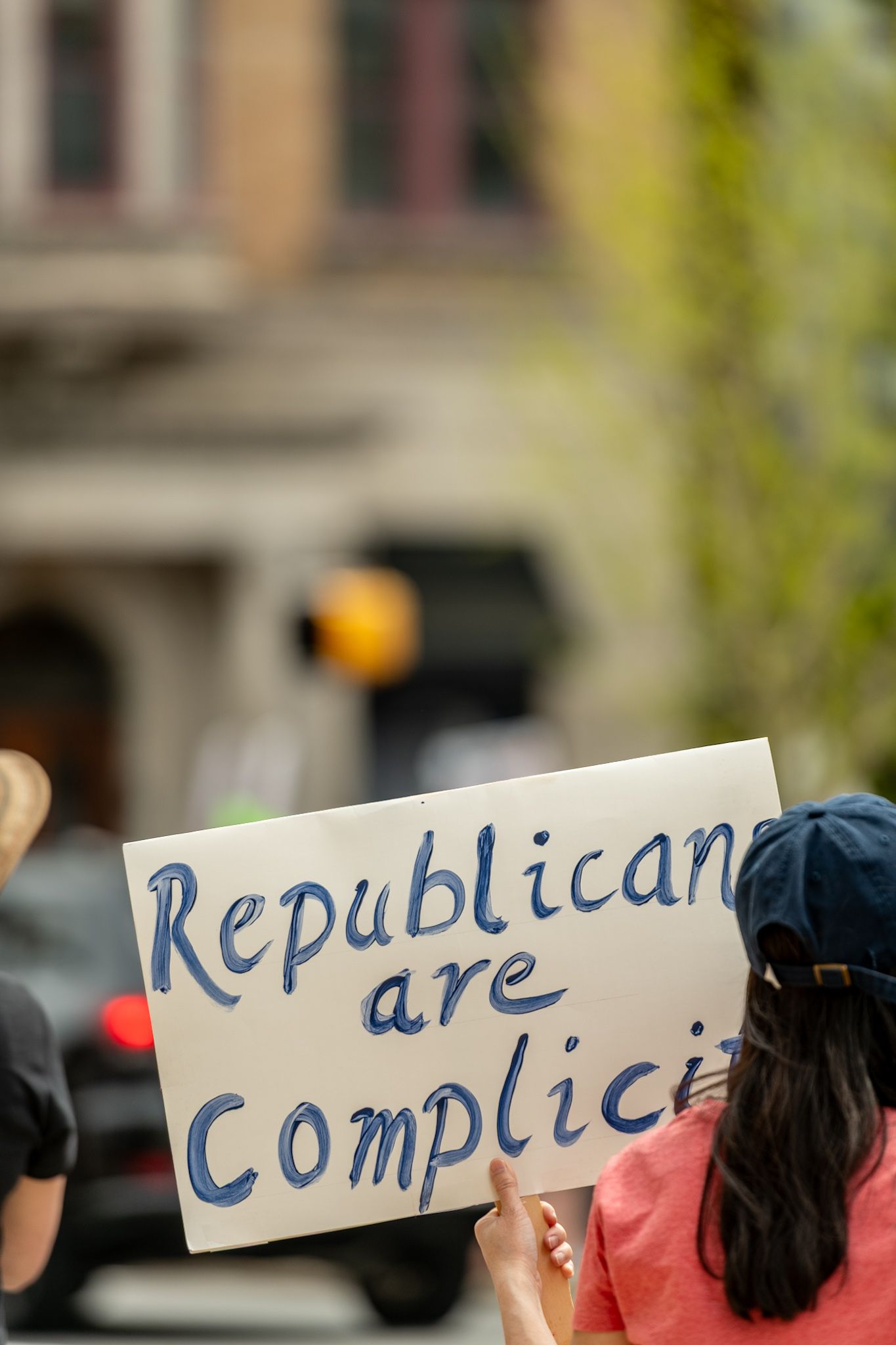Protest signs being held up at a demonstration with text about Republican complicity.