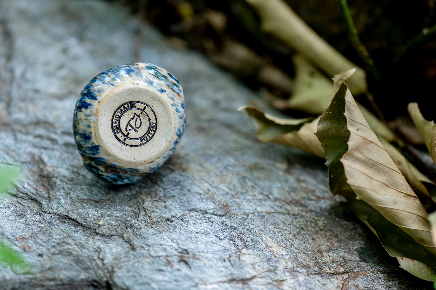 Bottom of a blue speckled stone duck figurine showing a circular Pandamonium brand logo.