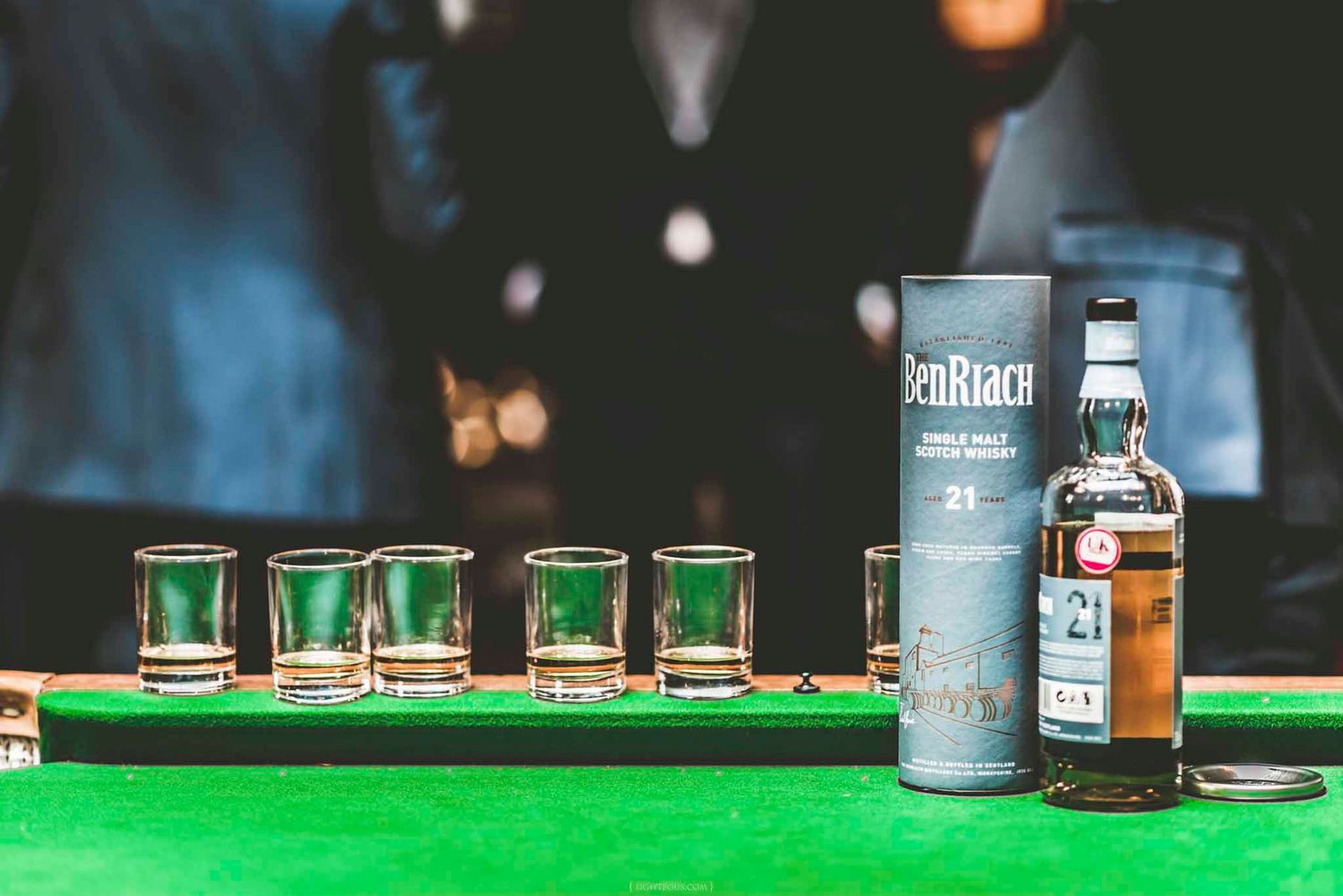 BenRiach 21 year single malt Scotch whisky bottle with shot glasses on a green billiard table.