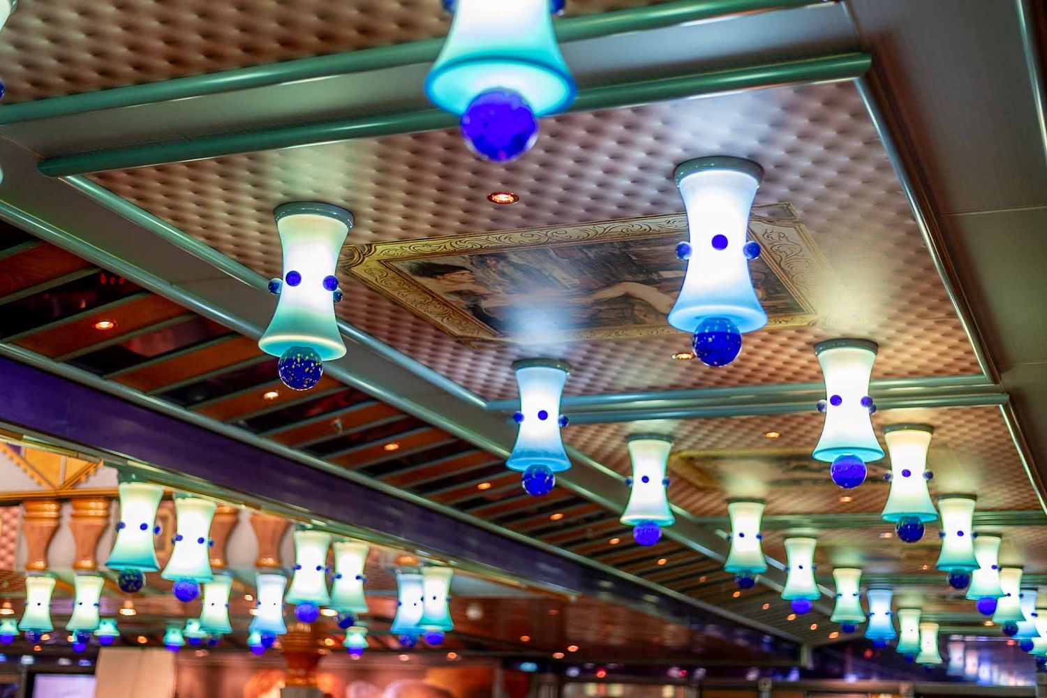 Row of illuminated blue and white decorative ceiling lights in a modern restaurant interior.